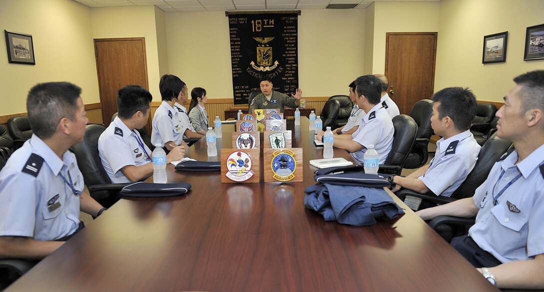 U. S. Air Force Lt. Col. Van Thai, 18th Operations Group deputy group commander, briefs Japan Air Self-Defense Force officers about the 18th OG's capabilities and mission of Kadena during a tour Sept. 16, 2015 at Kadena Air Base, Japan. The officers toured several aircraft operation group facilities and asked Airmen their questions and concerns while learning about Kadena's aircraft. (U.S. Air Force photo by Naoto Anazawa/Released)