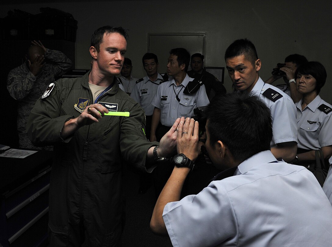 U.S. Air Force Capt. Steven Hendricks, 44th Fighter Squadron pilot, shows a night vision goggle to a Japan Air Self-Defense Force officer during a tour Sept. 16, 2015 at Kadena Air Base, Japan. The tour gave the JASDF officers a better understanding of the missions and operations of U.S. military aircraft on Kadena. (U.S. Air Force photo by Naoto Anazawa/Released) 
