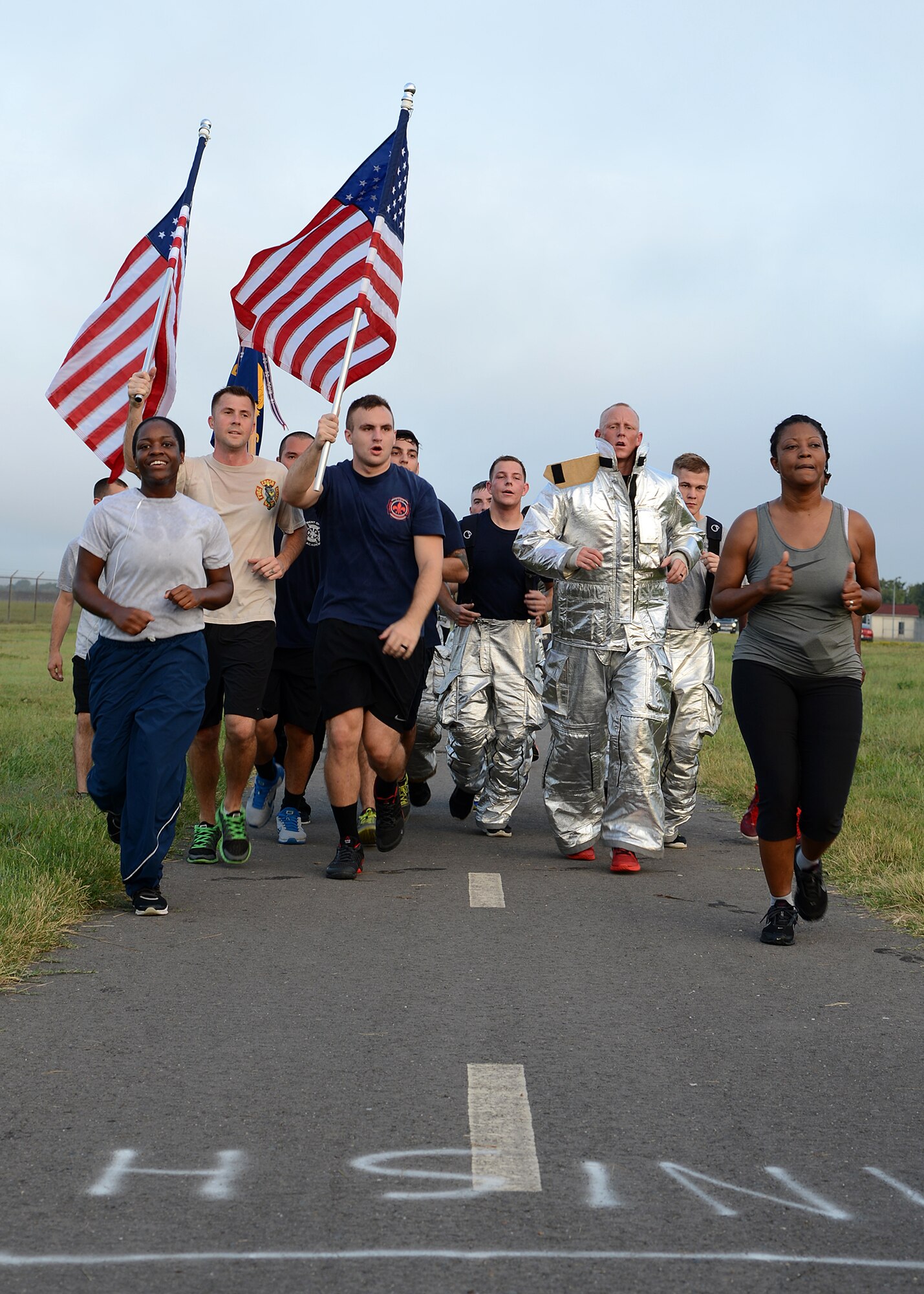 Members of Team Barksdale run with American flags during the Sept. 11 remembrance 5K Run on Barksdale Air Force Base La., Sept. 11, 2015. The flags were carried to honor the lives lost on this date 14 years ago. (U.S. Air Force photo/Senior Airman Joseph A. Pagán Jr.)