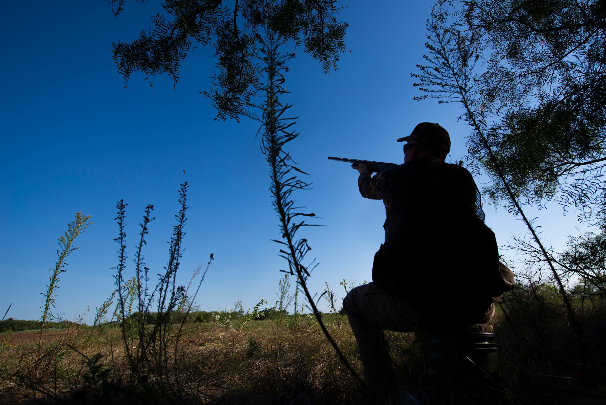 Staff Sgt. Daniel Cole, 364th Training Squadron instructor, points his shotgun at a dove passing by during the dove hunt portion of the Clay County Dove Salute in Henrietta, Texas, Sept. 12, 2015. Airmen were invited to the Birdwell and Clark Ranch to participate in dove hunt and a Texas-style steak dinner. (U.S. Air Force photo by Senior Airman Kyle Gese/Released)
