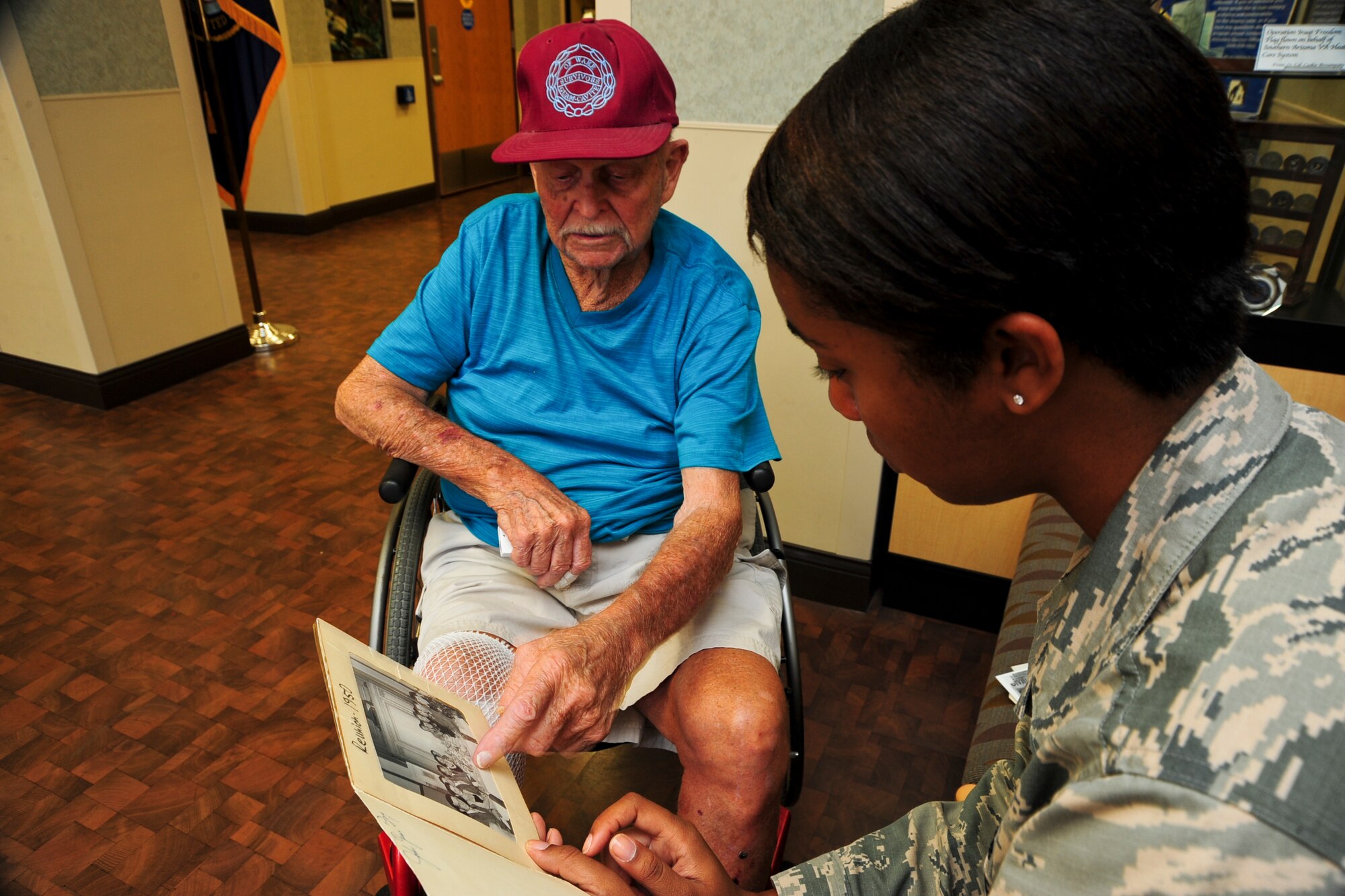 Malcolm Johnson, World War II veteran and former prisoner of war, shows U.S. Air Force Airman 1st Class Mya Crosby, 355th Fighter Wing Public Affairs photojournalist, a reunion photo of himself and fellow POWs at the Tucson Veterans Center in Tucson, Ariz., Aug. 18, 2015. Johnson was a civilian contractor when he was captured in December 1941, then put into internment camps throughout China and Japan for nearly four years. (U.S. Air Force photo by Senior Airman Chris Massey/Released)