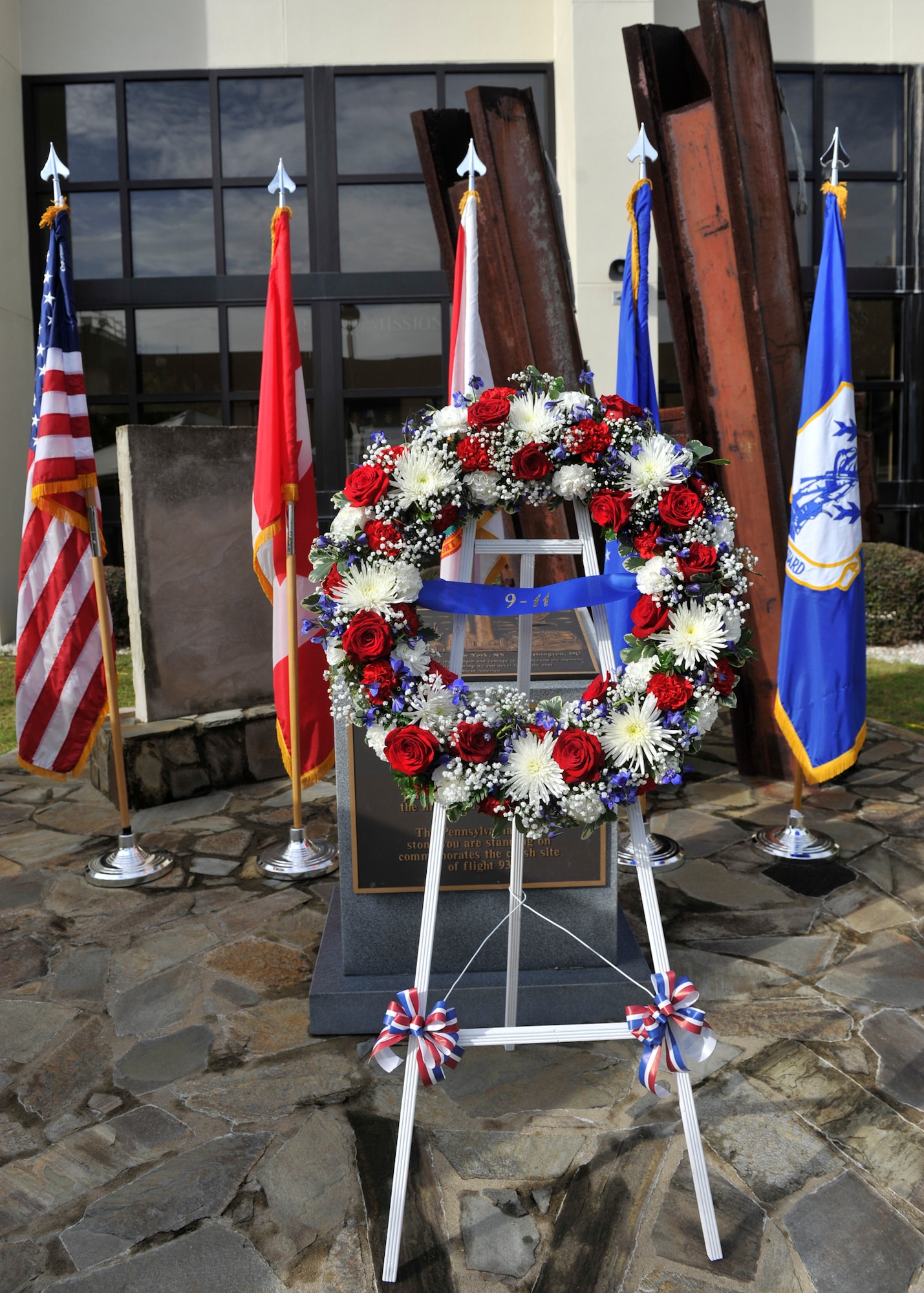 A wreath of red, white and blue flowers stands in front of the charred granite stone from the Pentagon at the 601st Air and Space Operations Center’s 9/11 Memorial Sept. 11. Placement of the wreath was part of a remembrance ceremony. (U.S. Air Force Photo by Airman 1st Class Sergio A. Gamboa/Released)