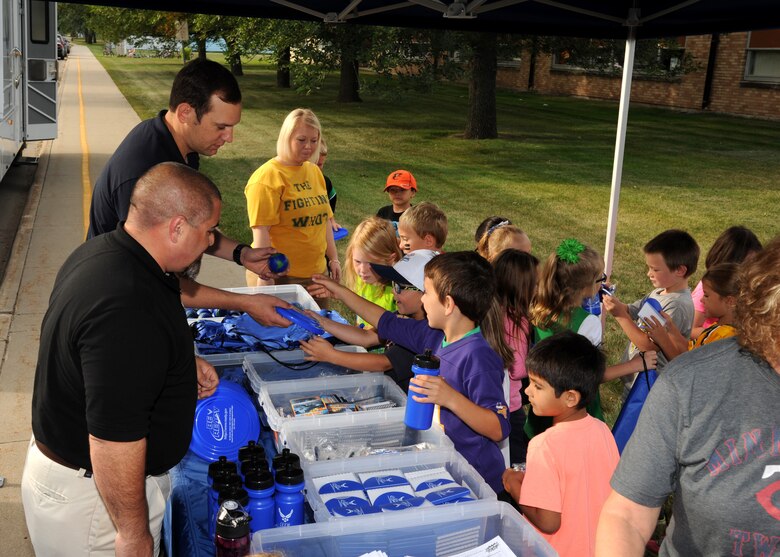 Shawn W. Leach, 319th Civil Engineer Squadron emergency management specialist, front, and Staff Sgt. Scott J. Tucker, 319th CES emergency management NCO-in-charge of logistics, hand out knick-knacks to Larimore Elementary School students Sept. 16, 2015, in Larimore, North Dakota. Leach and Tucker were part of the Grand Forks Air Force Base Emergency Management team that visited the school for National Preparedness Month. (U.S. Air Force photo by Airman 1st Class Ryan Sparks/Released)