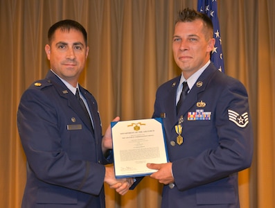 Major Robert Wryder Jr., 437th Aircraft Maintenance Squadron commander, presents the Air Force Commendation medal to SSgt. Marcus Williams, a 437th AMXS hydraulics craftsman, in the 437th AMXS auditorium at Joint Base Charleston – Air Base, Sept. 16, 2015. Williams received this reward for saving a civilian’s life after a motorcycle accident. (U.S. Air Force photo/Airman 1st Class Thomas T. Charlton)