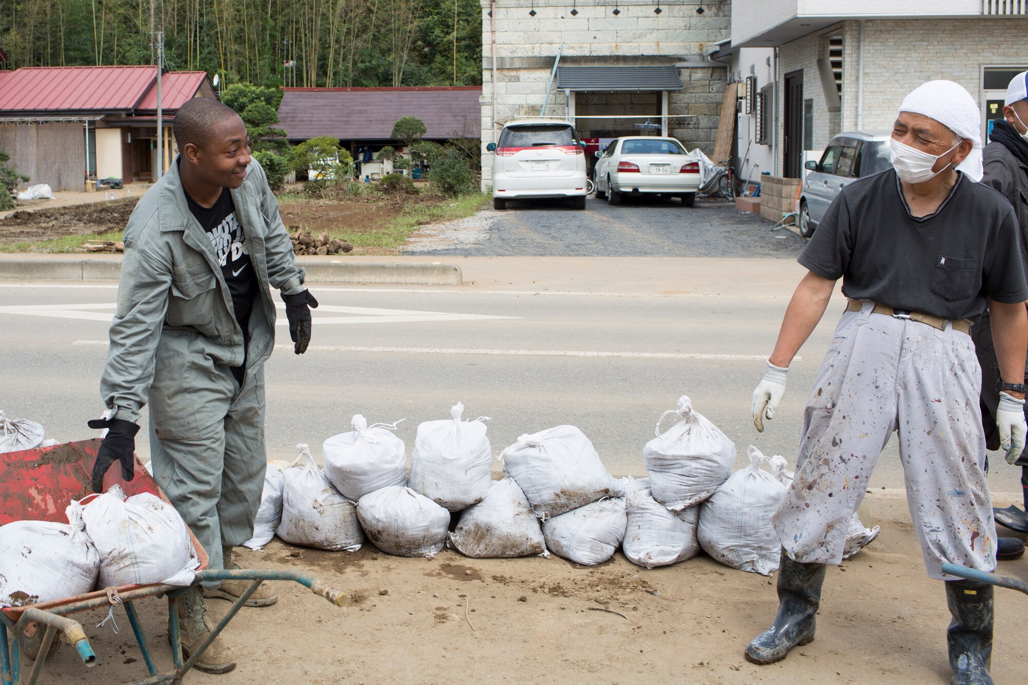 Tech. Sgt. Abdul Smith, 374th Civil Engineer Squadron, carries bags full of mud alongside a local resident at Kanuma city, Tochigi Prefecture, Japan, Sept. 15, 2015. Sixty Airmen and civil-ians from the 374th CES volunteered to help at sites in the Kasono area in support of floods and landslides caused by the heavy rainfall associated with the post-tropical remnant of Tropical Storm Etau, which stalled over eastern Japan, dumping up to 17 inches of rain in 24 hours, from Sept. 10 to Sept. 11. (U.S. Air Force photo by Osakabe Yasuo/Released)