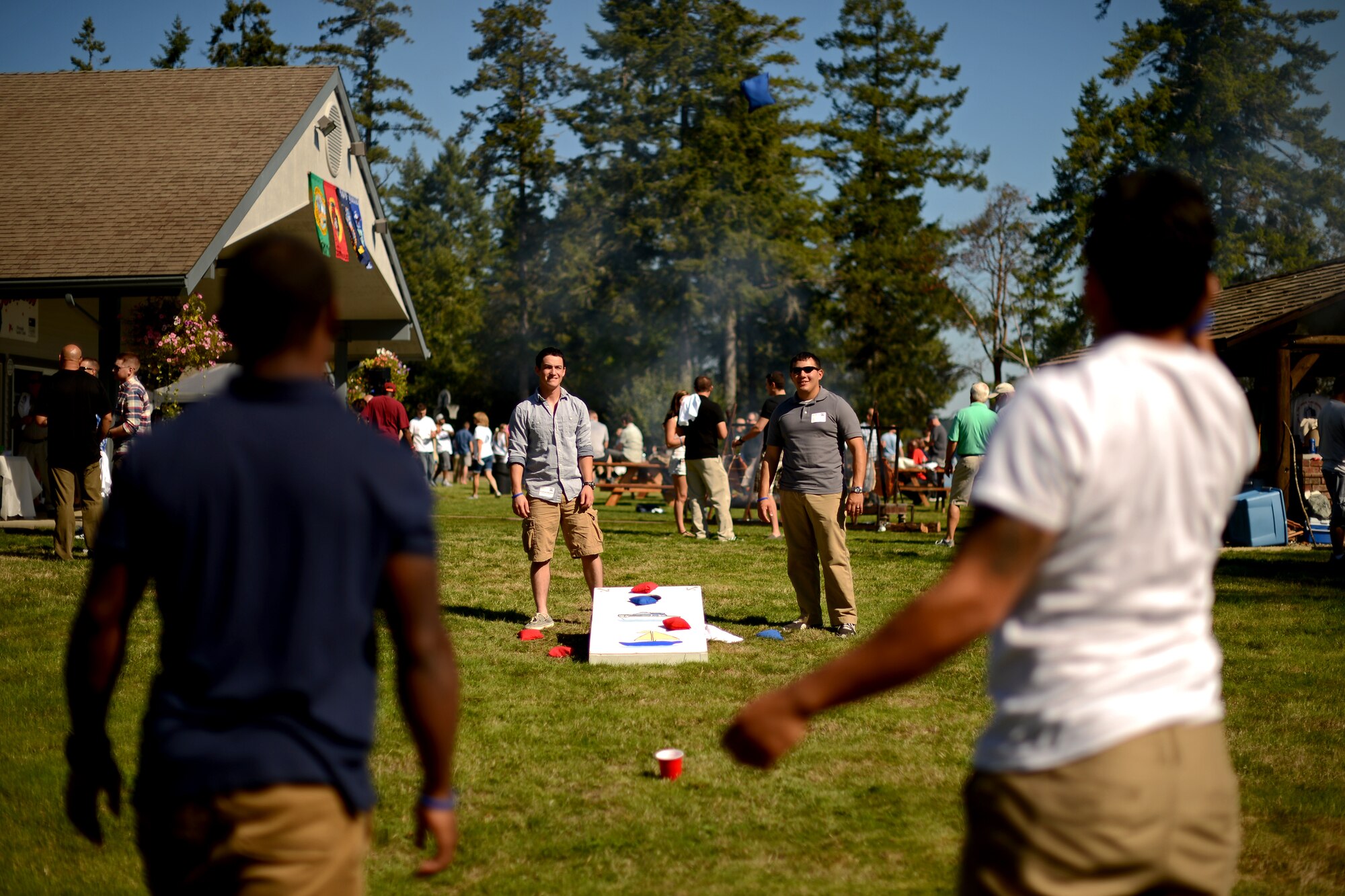 Service members, members of the Olympia Yacht Club and Thurston County Chamber of Commerce play corn hole Sept. 11, 2015, during Foofaraw at the Olympia Yacht Club Island Home, Wash. During the event, a flag lowering ceremony was held while ‘Taps’ played in honor of those lost on 9/11. (U.S. Air Force photo/Staff Sgt. Tim Chacon)