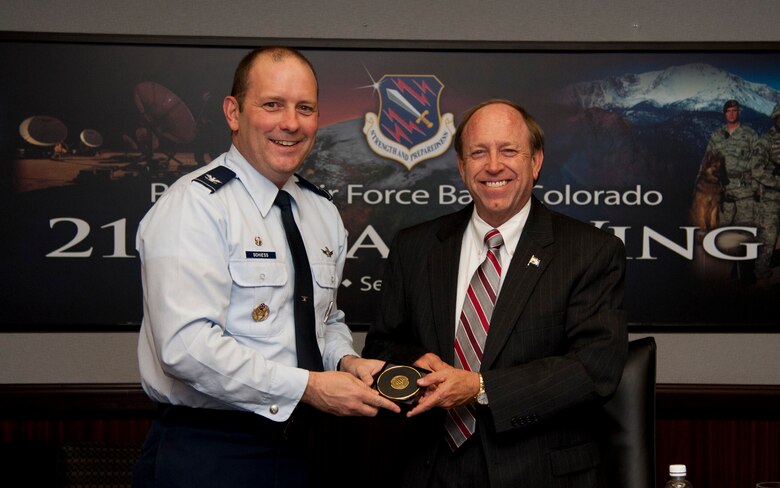 PETERSON AIR FORCE BASE, Colo. – Col. Doug Schiess, 21st Space Wing commander, presents John Suthers, the city of Colorado Springs mayor, with an official 21st SW coaster during an orientation and windshield tour, Sept. 15, 2015. Suthers and his staff were briefed on the Team Peterson and worldwide space assets and discussed future opportunities between the wing and the city. (U.S. Air Force photo by Senior Airman Tiffany DeNault) 