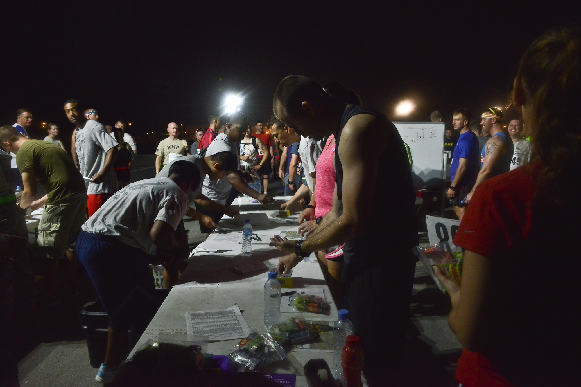 Runners sign up and collect their numbers and pre-run nutrition packs prior to the start of the 2015 Air Force Marathon Forward September 13, 2015 at Al Udeid Air Base, Qatar. This will mark seven years of U.S Air Force deployed location races overseas, with seven operating bases in theater participating. The first Air Force Marathon was held in 1997 at Wright-Patterson Air Force Base, Ohio. Since then, each marathon has been held the third Saturday of September, with an aircraft chosen each year to represent Air Force history in flight. (U.S. Air Force photo/ Staff Sgt. Alexandre Montes) 