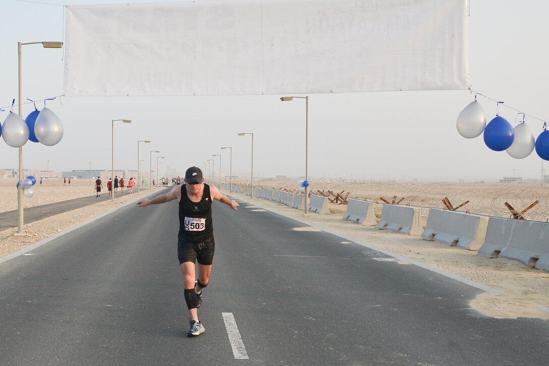 Maj. Tim Horn, US Army Central Command 4th Battlefield Coordination Detachment, crosses the finish line as the first male to complete 13.1 miles at the 2015 Air Force Marathon Forward September 13, 2015 at Al Udeid Air Base, Qatar. This will mark seven years that the race has taken place at seven operating bases in theater. The first Air Force Marathon was held in 1997 at Wright-Patterson Air Force Base, Ohio. Since then, each marathon has been held the third Saturday of September, with an aircraft chosen each year to represent Air Force history in flight. (U.S. Air Force photo/ Staff Sgt. Alexandre Montes) 