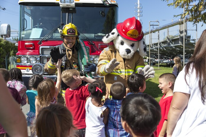 Students with Matthew C. Perry Elementary School gather around to greet Eiji Aridome, a fire fighter aboard station, and, Sparky,  the air station’s fire safety dog, during M.C. Perry Elementary and High School’s 9/11 Remembrance Walk aboard Marine Corps Air Station Iwakuni, Japan, Sept. 11, 2015.  Beginning at 9:11 a.m., this is the third annual walk hosted by the schools and an event that helps students understand the significance of never forgetting, according to Devin Johnston-Lee, fire chief for the air station.