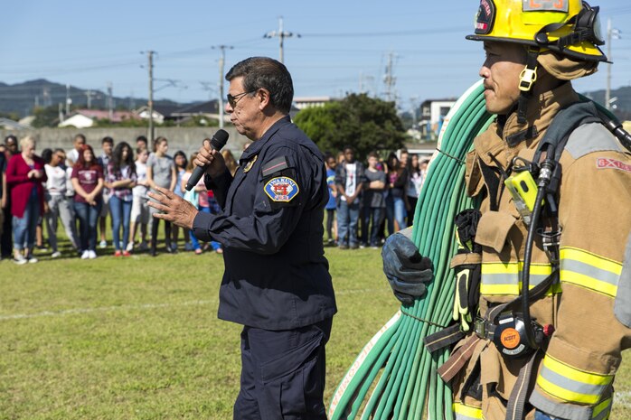 Devin Johnston-Lee, fire chief for the air station, speaks to Matthew C. Perry Elementary and High School students during M.C. Perry Elementary and High School’s 9/11 Remembrance Walk aboard Marine Corps Air Station Iwakuni, Japan, Sept. 11, 2015.  Johnston-Lee spoke to the students about the importance of remembering 9/11 and getting them to understand that everyday citizens do heroic things, not because they’re not afraid, but because they are afraid and are still willing to do their job.