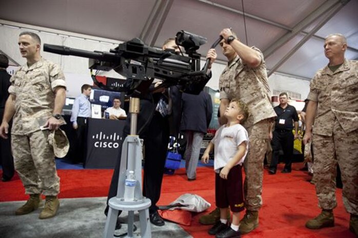 Maj. John R. Bitonti II, Headquarters and Service Battalion, helps his son try out the latest weapon technology on display during the Modern Day Marine Military Exposition at Marine Corps Base Quantico, Va., Sept. 29. Although many of the products were not currently in use by the Corps, the exposition gave vendors the opportunity to promote their products to Marines.