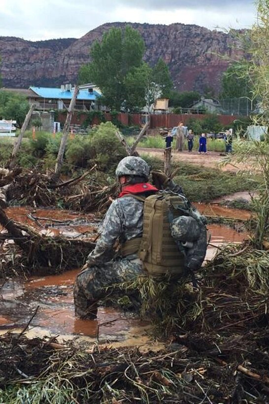 A Utah Army National Guardsman wades through mud and water while conducting search and rescue efforts for survivors following the deadly flooding near the border town of Hildale, Utah, Sept. 16, 2015.