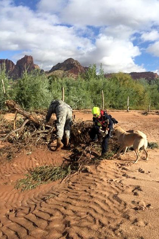 A local first responder, search dog and Utah Army National Guardsmen conduct their search and rescue efforts for survivors following the deadly flooding near the border town of Hildale, Utah, Sept. 16, 2015.