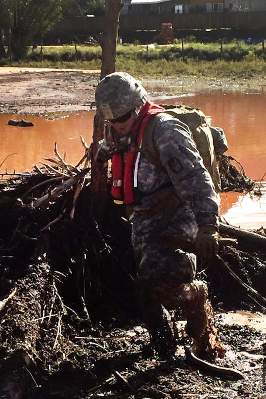 A Utah Army National Guardsman wades through mud and water while conducting search and rescue efforts for survivors following the deadly flooding near the border town of Hildale, Utah, Sept. 16, 2015.