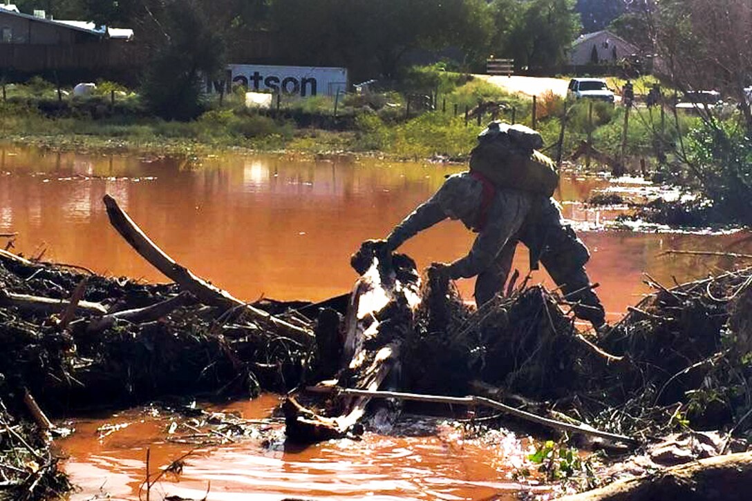 A Utah Army National Guardsman wades through mud and water while conducting search and rescue efforts for survivors following the deadly flooding near the border town of Hildale, Utah, Sept. 16, 2015.