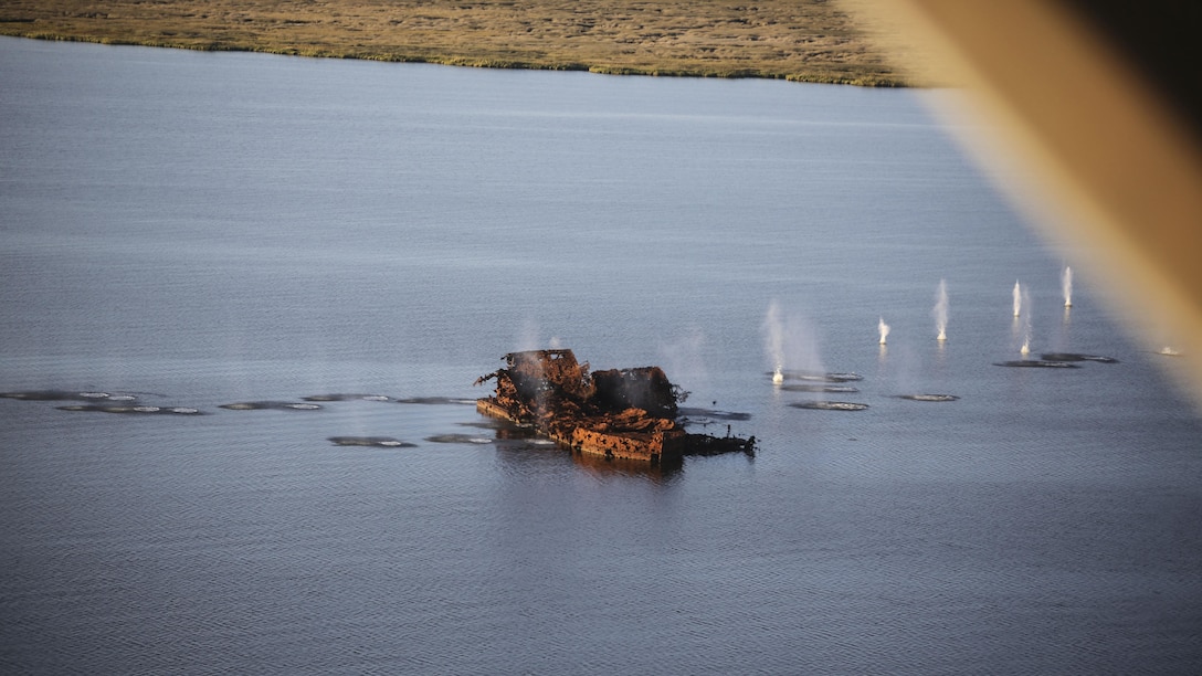 Marines with Marine Medium Tiltrotor Squadron 365 make impact on targets utilizing the GAU-16 .50 caliber machine gun in an MV-22B Osprey in the skies above Piney Island bombing range, North Carolina, Sept. 15, 2015. The crew flew over training area Bombing Target 11 to assault targets resembling a convoy, barge and landing craft. 