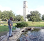 Fort Sam Houston Quadrangle animal caretaker Adam Quintero scans the pond in the southeast corner of the area prior to cleaning. Pond maintenance is one of the many duties Quintero performs to take care of the Quad’s many deer, ducks, peacocks and fish.