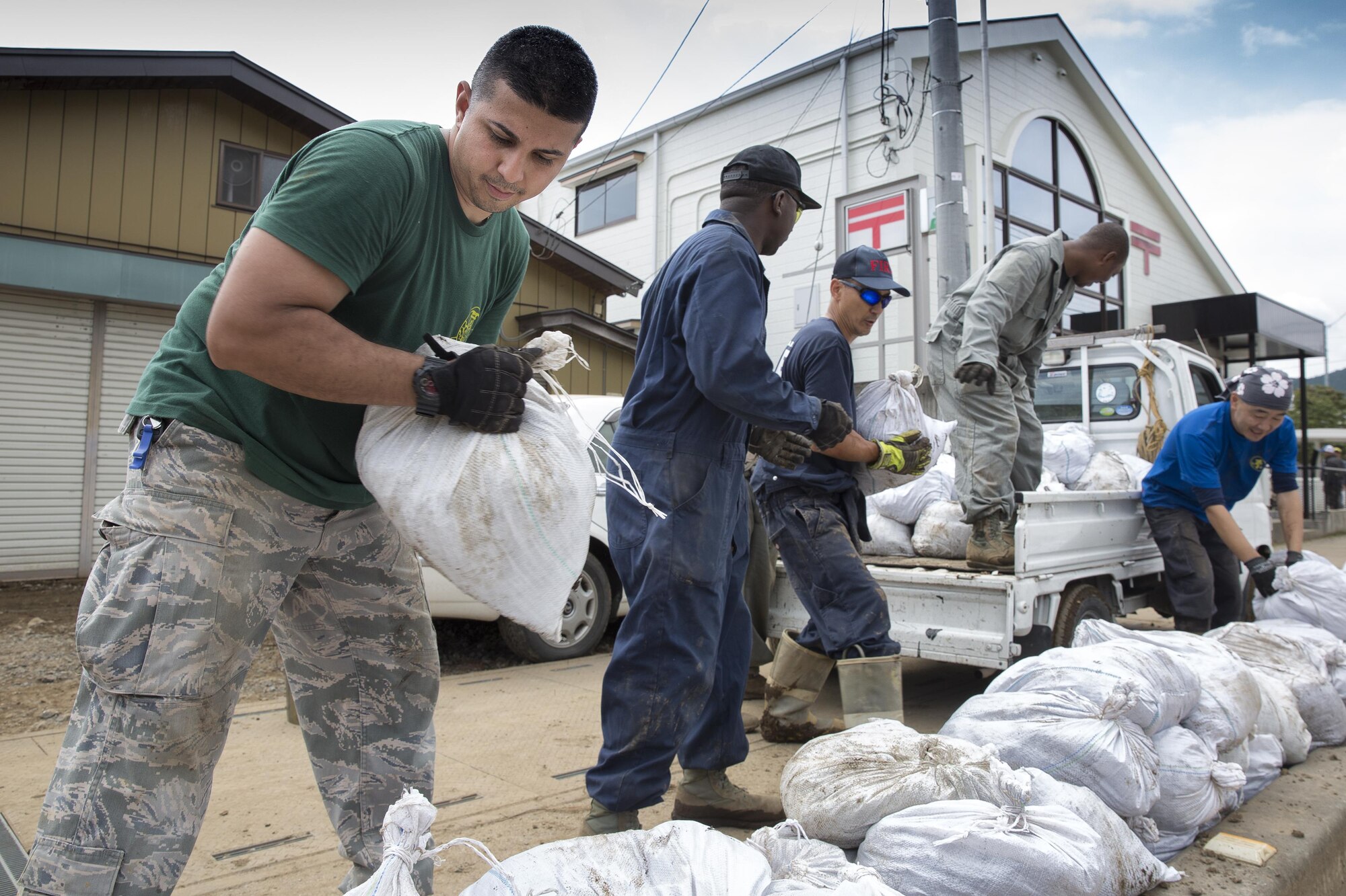 Volunteers from the 374th Civil Engineer Squadron establish an assembly line to download bags full of mud from a transport truck at Kanuma City, Tochigi Prefecture, Japan, Sept. 15, 2015. Sixty Airmen and civilians from the 374th CES volunteered to help at sites in the Kasono area in support of floods and landslides caused by the heavy rainfall associated with the post-tropical remnant of Tropical Storm Etau, which stalled over eastern Japan, dumping up to 17 inches of rain in 24 hours, from Sept. 10 to Sept. 11. (U.S. Air Force photo by Osakabe Yasuo/Released)