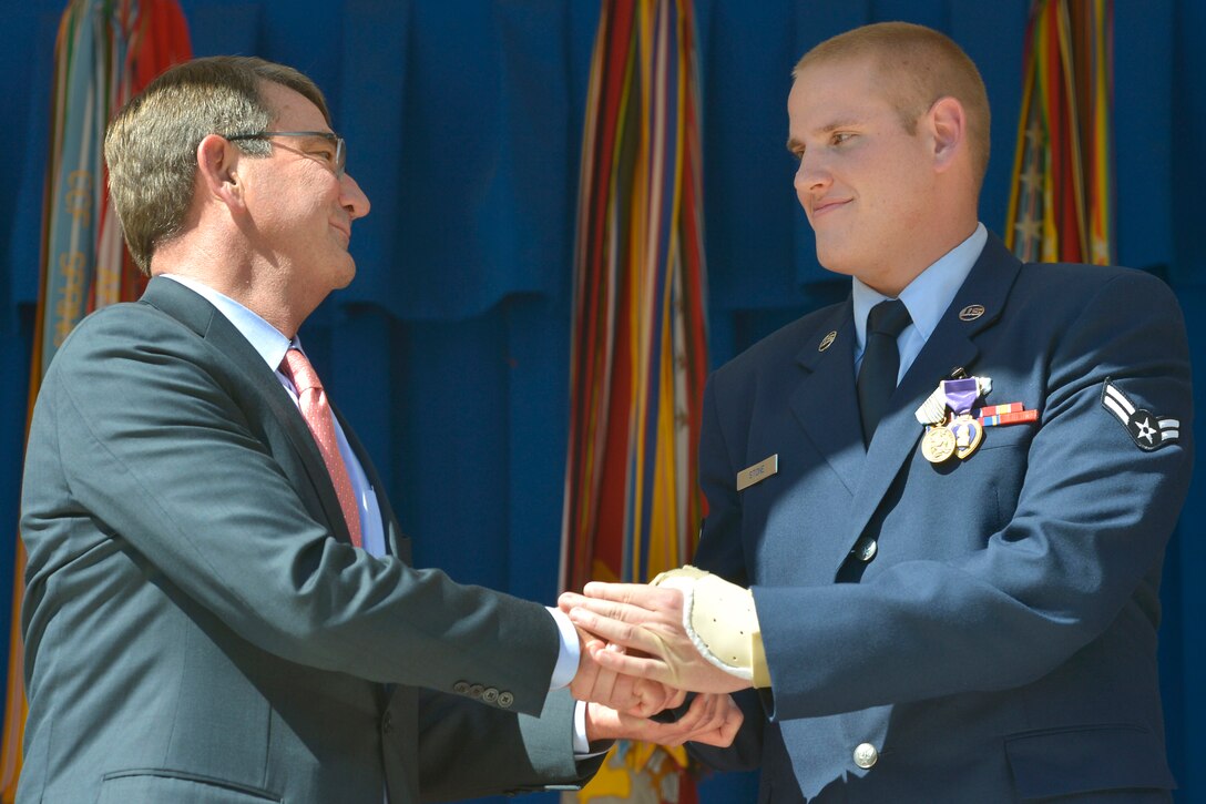 Defense Secretary Ash Carter congratulates Purple Heart and Airman's Medal recipient Air Force Airman 1st Class Spencer Stone during an awards ceremony at the Pentagon, Sept. 17, 2015. Stone and two others were honored for taking immediate action to subdue an armed gunman before he could engage his automatic weapon on the train outside of Brussels last month.