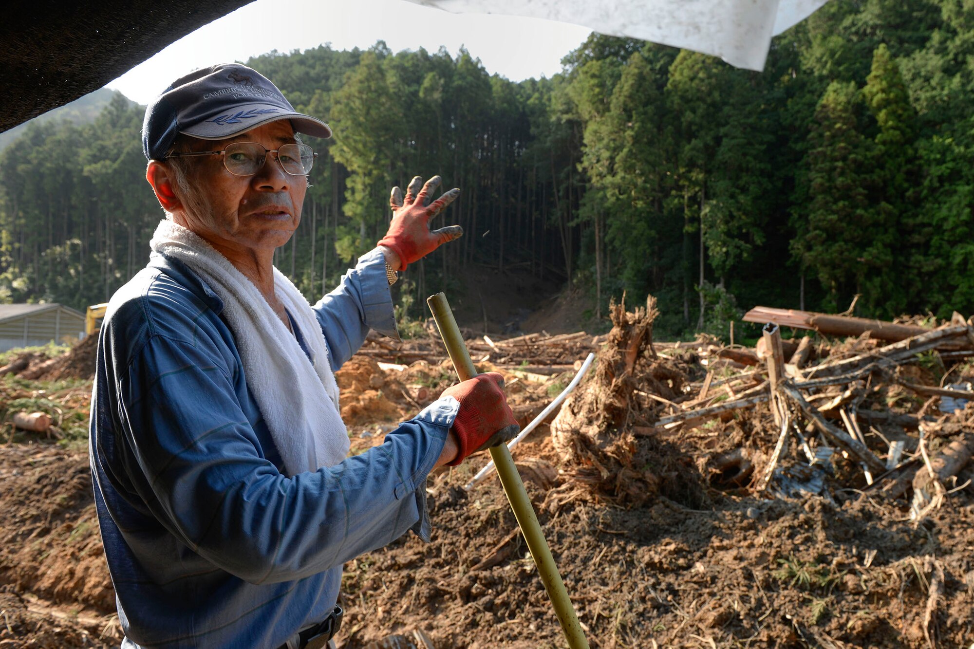 Sota Watanabe, a local farmer, explains how a landslide destroyed much of his property at Kanuma City, Tochigi prefecture, Sept. 15, 2015. More than 60 volunteers, Airmen and Japanese workers from Yokota Air Base, spent three days helping farmers remove mud and debris from their fields and irrigation systems and cleaning yards and driveways for elderly citizens. (U.S. Air Force photo by Staff Sgt. Cody H. Ramirez/Released)