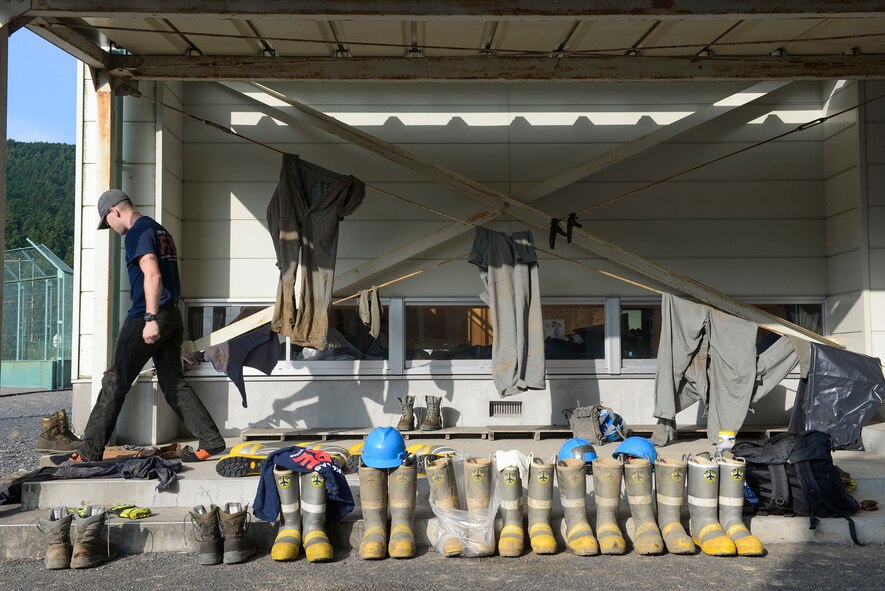 A volunteer with the 374th Civil Engineer fire protection searches for his boots early in the morning outside the gym of an elementary school at Kanuma City, Tochigi prefecture, Japan, Sept. 15, 2015. The volunteers, more than 60 Airmen and Japanese who work at Yokota Air Base, helped remove thousands of pounds of mud from the many businesses, buildings and personal homes that were damaged during floods and landslides in the Tochigi area. (U.S. Air Force photo by Staff Sgt. Cody H. Ramirez/Released)