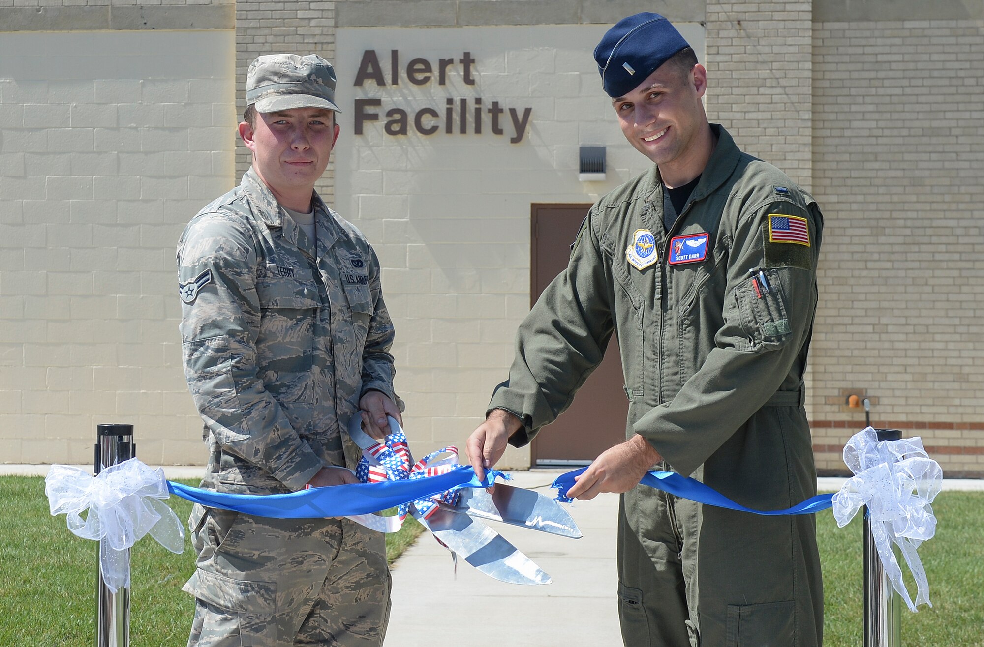 Airman 1st Class Justin Terry, 22nd Civil Engineer Squadron electrical systems apprentice and 1st Lieutenant Scott Darr officially reopen the new Alert Facility with a ribbon cutting ceremony, Sept. 10, 2015, at McConnell Air Force Base, Kan. Members of the 22nd and 931st CES renovated the building for four months, creating 15 bedroom now capable of housing the alert crews. (U.S. Air Force photo by Senior Airman Colby L. Hardin)
