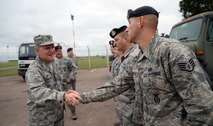 U.S. Air Force Col. Thomas D. Torkelson, left, 100th Air Refueling Wing commander, is greeted by U.S. Air Force Staff Sgt. Joseph Serrano, 100th Security Force Squadron Military Working Dog kennel master and trainer, Sept. 8, 2015, on RAF Mildenhall, England. Torkelson walked around with the team as they were conducting a sweep for aids during an initial detection certification. (U.S. Air Force photo by Senior Airman Christine Halan/Released)