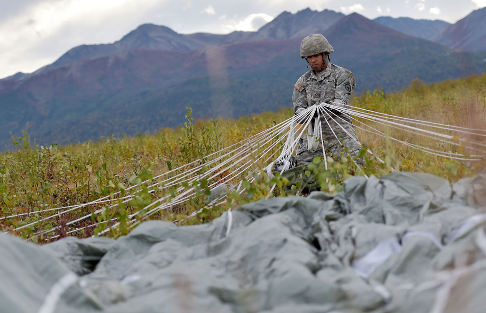 Army Pfc. Malcolm Troyle assigned to E Company, 6th Brigade Engineer Battalion, 4th Infantry Brigade Combat Team (Airborne), 25th Infantry Division, U.S. Army Alaska, Albuquerque, N.M., pulls on the suspension lines of his parachute after conducting an airborne operation with USARAK Commanding General Army Maj. Gen. Bryan Owens from CH-47 Chinook helicopters over Malemute drop zone on Joint Base Elmendorf-Richardson, Alaska, Sept. 10, 2015. USARAK is a central component to the Army’s rebalance to the Pacific, providing two fully mission-ready Brigade Combat Teams ready to position unit elements anywhere across the Pac-Rim within 18 hours notice, and is uniquely positioned within nine-hours flight time from 90 percent of the world’s most highly-populated regions. (U.S. Air Force photo/Justin Connaher)