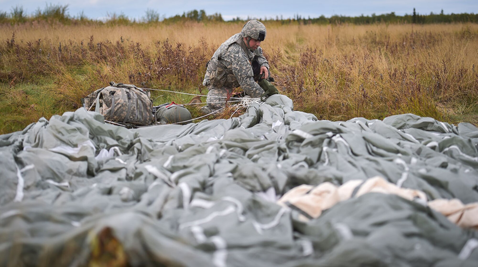 Army Sgt. Jeremy Twomey assigned to C Company, 6th Brigade Engineer Battalion, 4th Infantry Brigade Combat Team (Airborne), 25th Infantry Division, U.S. Army Alaska, Riverside Calif., packs up his parachute after conducting an airborne operation with USARAK Commanding General Army Maj. Gen. Bryan Owens from CH-47 Chinook helicopters over Malemute drop zone on Joint Base Elmendorf-Richardson, Alaska, Sept. 10, 2015.  USARAK is a central component to the Army’s rebalance to the Pacific, providing two fully mission-ready Brigade Combat Teams ready to position unit elements anywhere across the Pac-Rim within 18 hours notice, and is uniquely positioned within nine-hours flight time from 90 percent of the world’s most highly-populated regions. (U.S. Air Force photo/Justin Connaher)