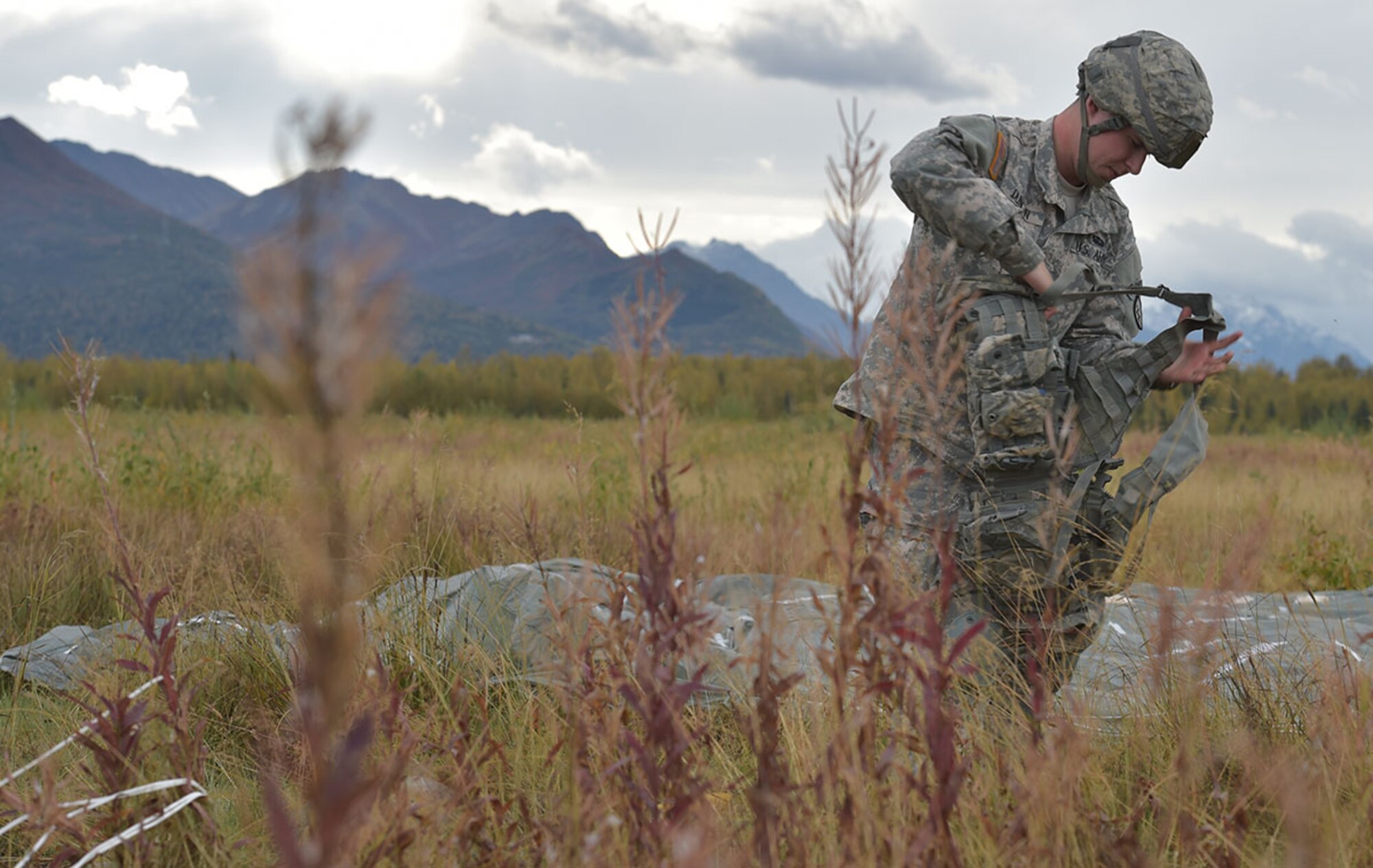 Army Pfc. Rodney Duncan, assigned to C Company, 6th Brigade Engineer Battalion, 4th Infantry Brigade Combat Team (Airborne), 25th Infantry Division, U.S. Army Alaska, a native of Paradise, Calif., puts on his personal equipment after conducting an airborne operation with USARAK Commanding General Army Maj. Gen. Bryan Owens from CH-47 Chinook helicopters over Malemute drop zone on Joint Base Elmendorf-Richardson, Alaska, Sept. 10, 2015.  USARAK is a central component to the Army’s rebalance to the Pacific, providing two fully mission-ready Brigade Combat Teams ready to position unit elements anywhere across the Pac-Rim within 18 hours notice, and is uniquely positioned within nine-hours flight time from 90 percent of the world’s most highly-populated regions. (U.S. Air Force photo/Justin Connaher)