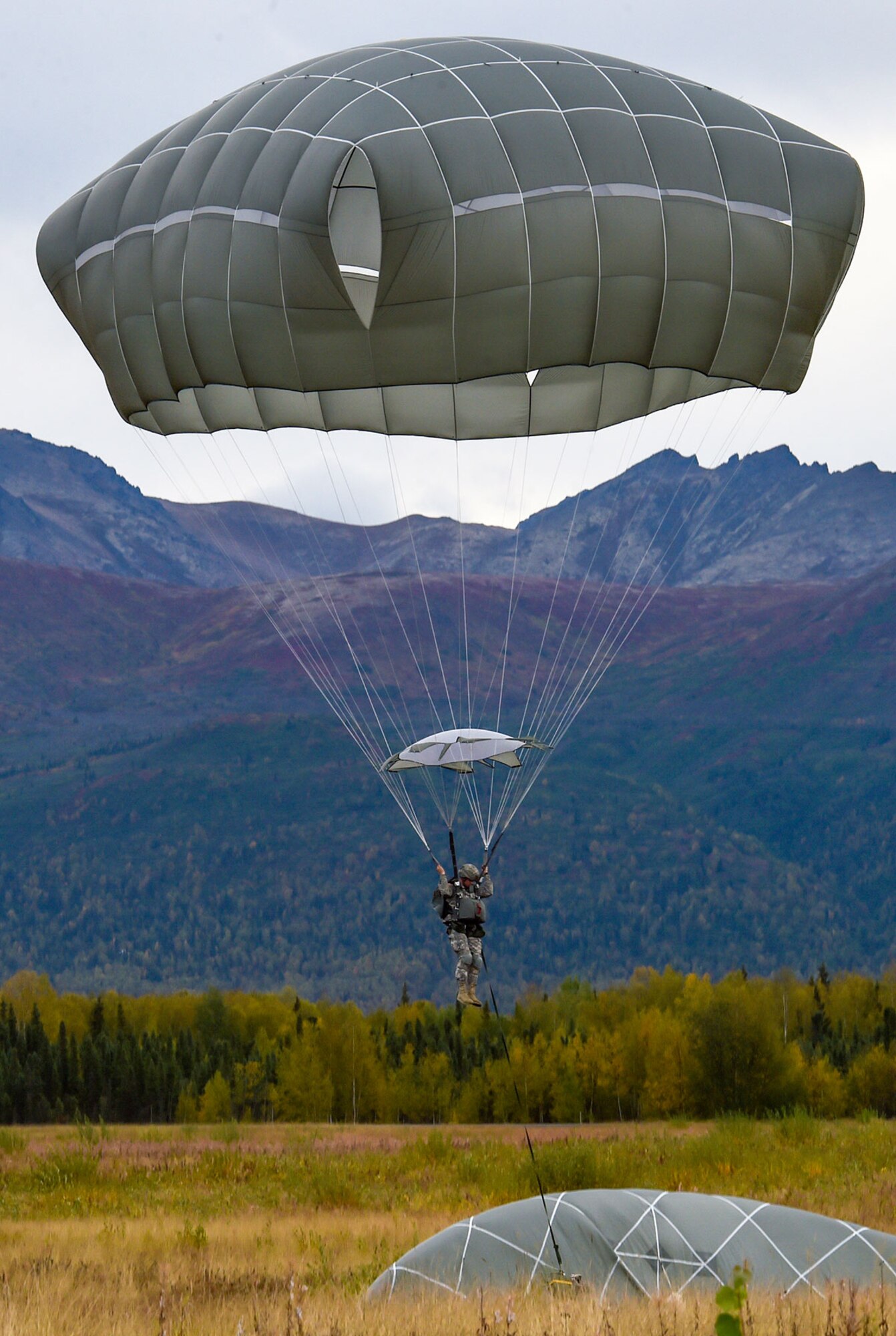 A Soldier assigned to U.S. Army Alaska prepares to land while conducting an airborne operation with USARAK Commanding General Army Maj. Gen. Bryan Owens from CH-47 Chinook helicopters over Malemute drop zone on Joint Base Elmendorf-Richardson, Alaska, Sept. 10, 2015.  USARAK is a central component to the Army’s rebalance to the Pacific, providing two fully mission-ready Brigade Combat Teams ready to position unit elements anywhere across the Pac-Rim within 18 hours notice, and is uniquely positioned within nine-hours flight time from 90 percent of the world’s most highly-populated regions. (U.S. Air Force photo/Justin Connaher)