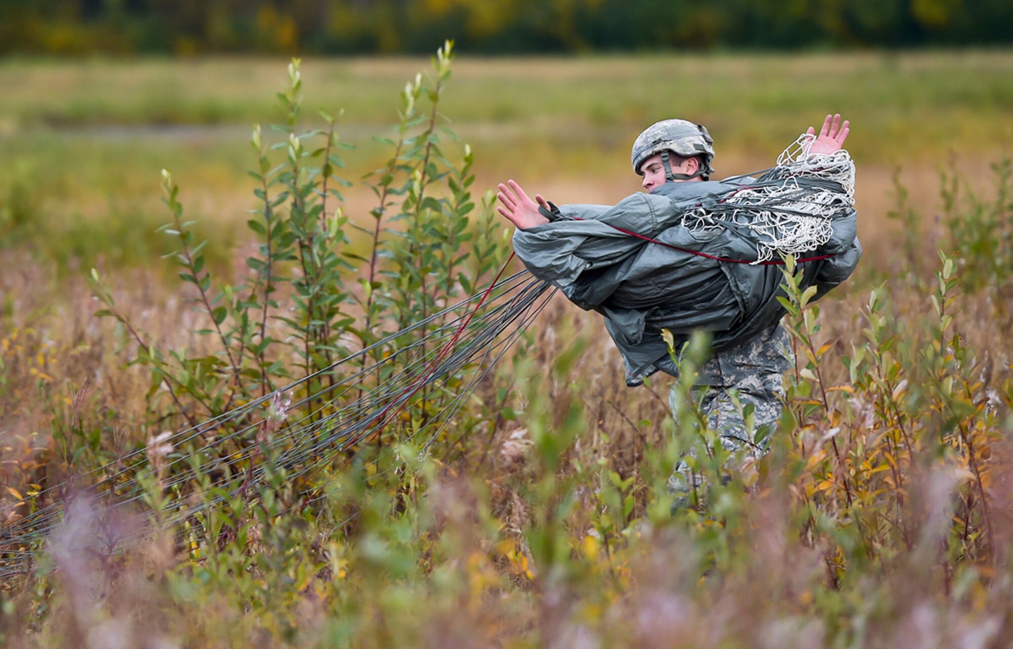 A Soldier assigned to U.S. Army Alaska rolls up his parachute after conducting an airborne operation with USARAK Commanding General Army Maj. Gen. Bryan Owens from CH-47 Chinook helicopters over Malemute drop zone on Joint Base Elmendorf-Richardson, Alaska, Sept. 10, 2015.  USARAK is a central component to the Army’s rebalance to the Pacific, providing two fully mission-ready Brigade Combat Teams ready to position unit elements anywhere across the Pac-Rim within 18 hours notice, and is uniquely positioned within nine-hours flight time from 90 percent of the world’s most highly-populated regions. (U.S. Air Force photo/Justin Connaher)