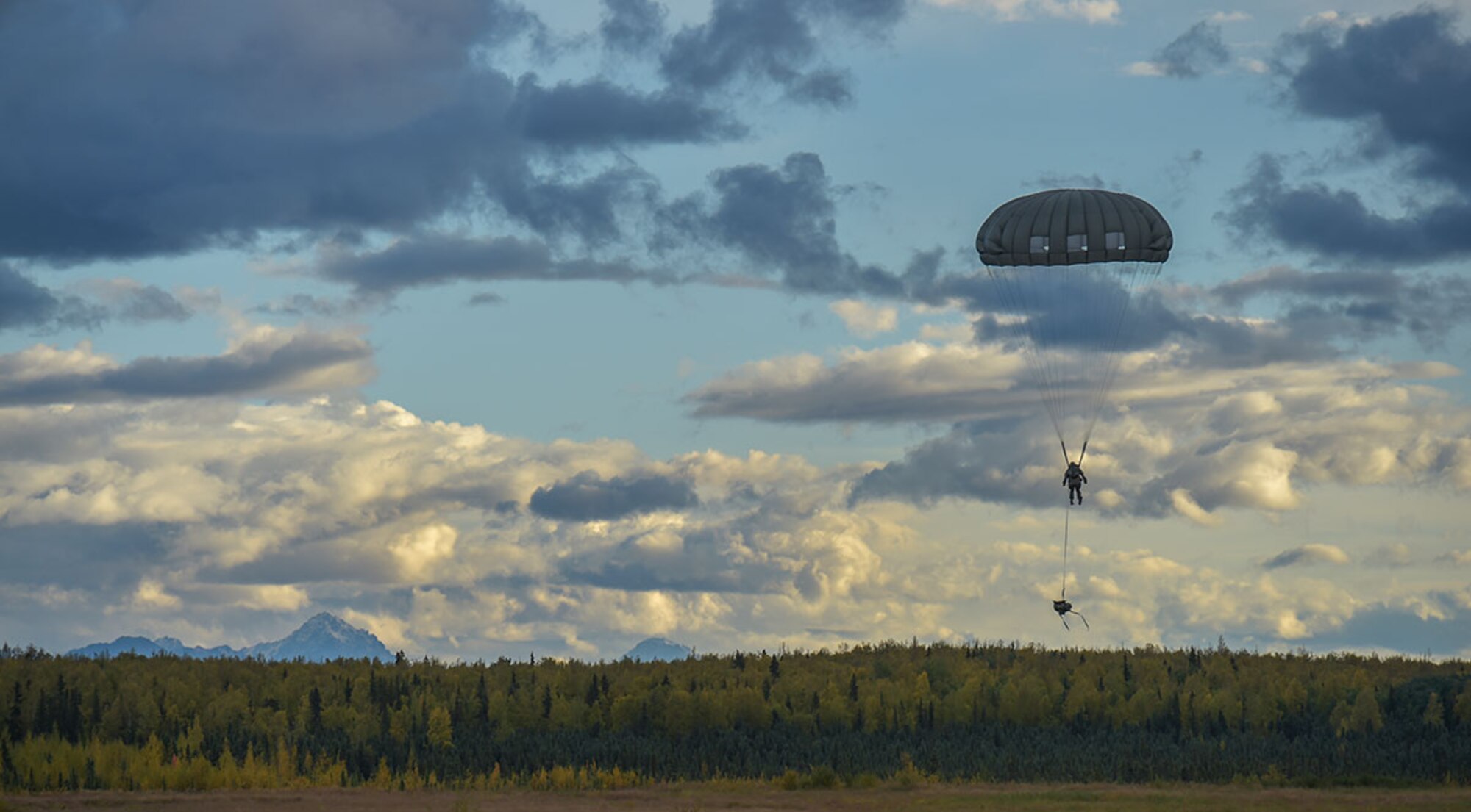 A Soldier assigned to U.S. Army Alaska lowers his rucksack as he prepares to land while conducting an airborne operation with USARAK Commanding General Army Maj. Gen. Bryan Owens from CH-47 Chinook helicopters over Malemute drop zone on Joint Base Elmendorf-Richardson, Alaska, Sept. 10, 2015. USARAK is a central component to the Army’s rebalance to the Pacific, providing two fully mission-ready Brigade Combat Teams ready to position unit elements anywhere across the Pac-Rim within 18 hours notice, and is uniquely positioned within nine-hours flight time from 90 percent of the world’s most highly-populated regions. (U.S. Air Force photo/Justin Connaher)