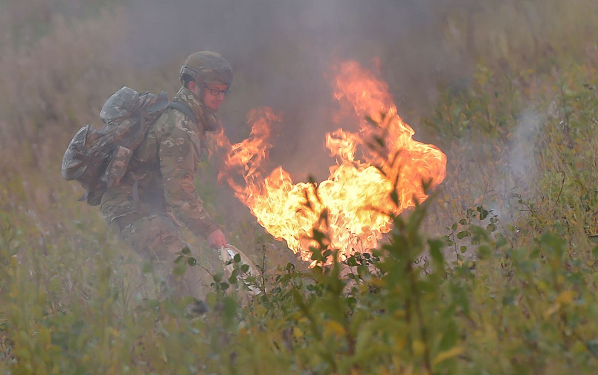 A U.S. Air Force Airman tends to a smoke pot as Soldiers assigned to U.S. Army Alaska conduct an airborne operation with USARAK Commanding General Army Maj. Gen. Bryan Owens from CH-47 Chinook helicopters over Malemute drop zone on Joint Base Elmendorf-Richardson, Alaska, Sept. 10, 2015.  USARAK is a central component to the Army’s rebalance to the Pacific, providing two fully mission-ready Brigade Combat Teams ready to position unit elements anywhere across the Pac-Rim within 18 hours notice, and is uniquely positioned within nine-hours flight time from 90 percent of the world’s most highly-populated regions. (U.S. Air Force photo/Justin Connaher)