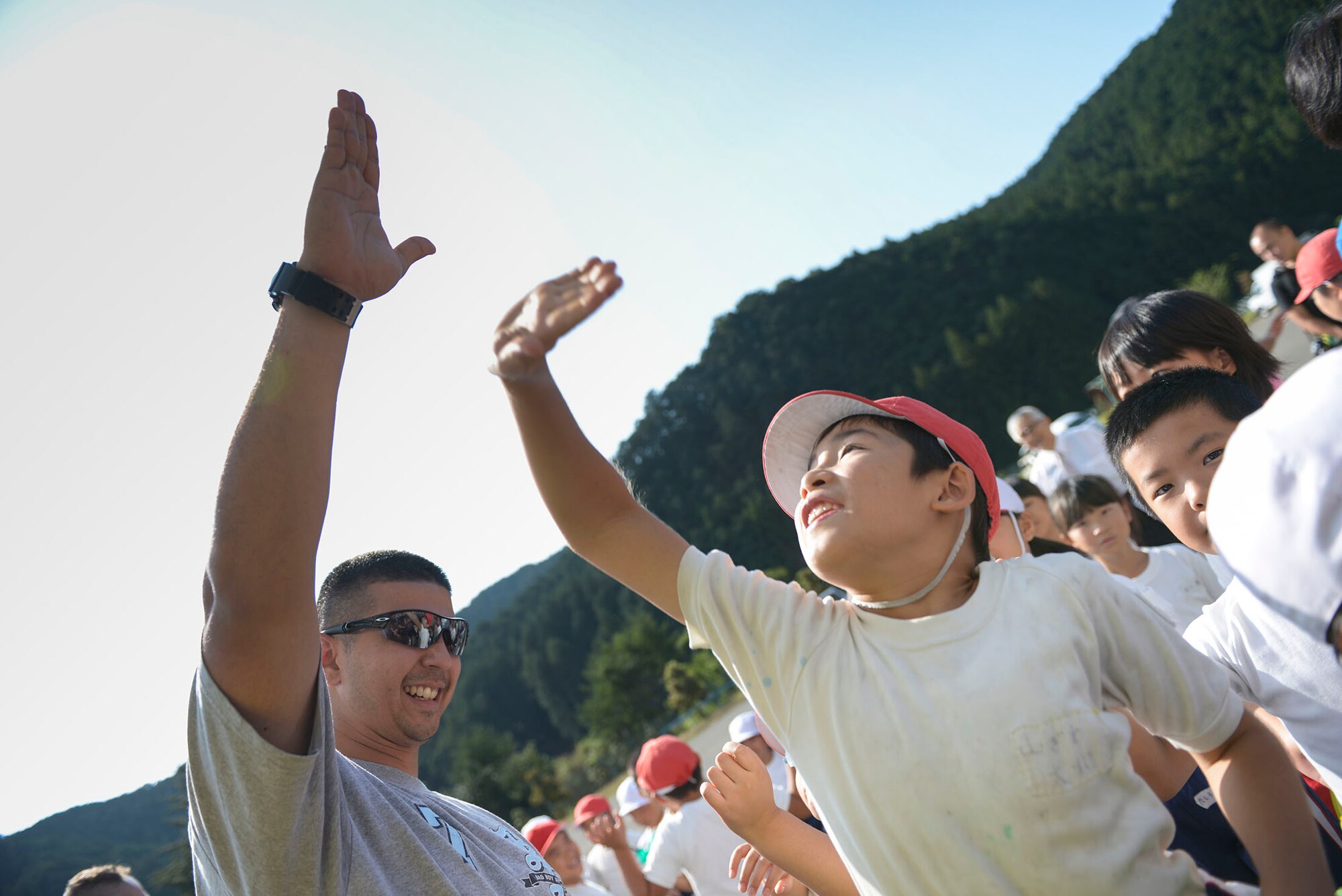A volunteer from Yokota Air Base raises his hand high above local students after a
'thank you' presentation at Kanuma City, Tochigi Prefecture, Japan, Sept. 15, 2015.
More than 60 Airmen and Japanese who work at Yokota Air Base to help remove
thousands of pounds of mud from the many businesses, buildings and personal homes
that were damaged during floods and landslides in the Tochigi area. Students at the
local elementary school made a speech and sang a song to thank the volunteers for
their efforts in the community. (U.S. Air Force photo by Staff Sgt. Cody H. Ramirez/
Released)