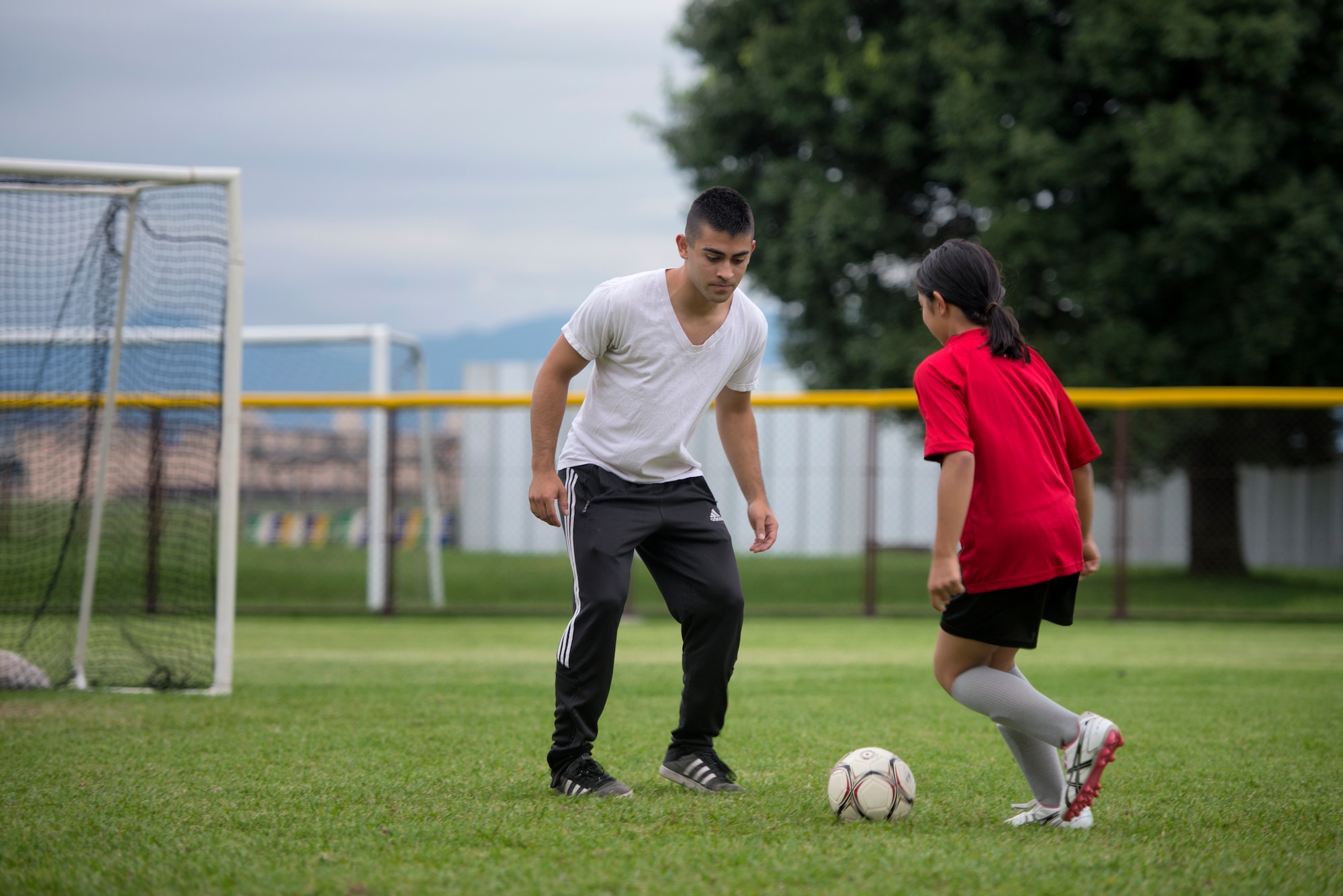 Airman 1st Class Tomasz Barba, volunteer soccer coach, practices a handling technique with a youth soccer participant at Yokota Air Base, Japan, Sept. 15, 2015. Yokota’s Youth Sports Program is extensive and relies upon hundreds of volunteers to serve as coaches, assistant coaches, and team parents. (U.S. Air Force photo by Airman 1st Class Delano Scott/Released)