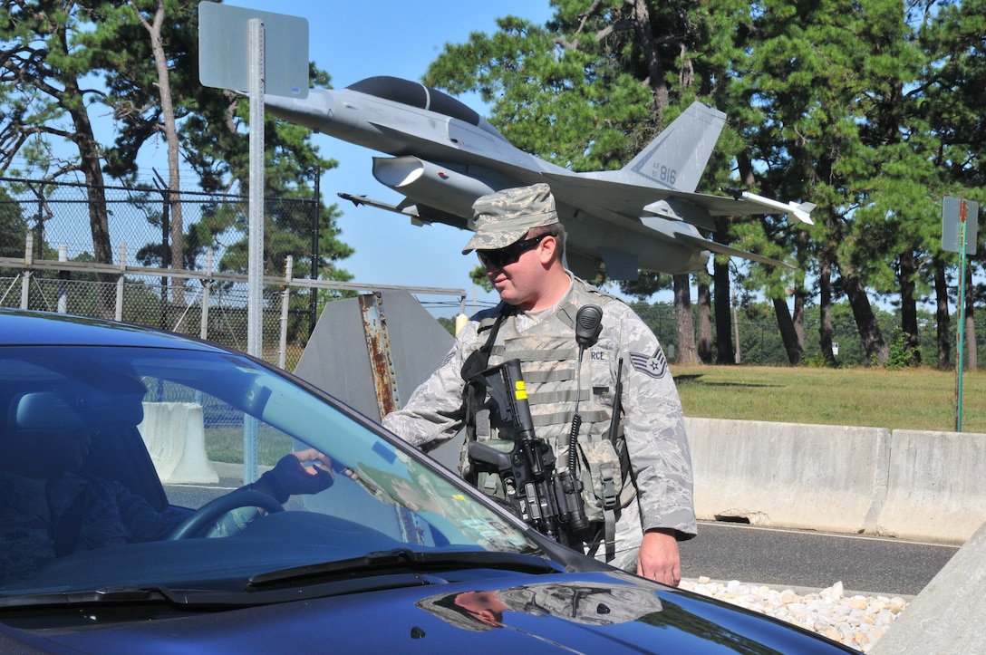 U.S. Air Force Staff Sgt. Ryan Fogarty, fire protection specialist with the New Jersey Air National Guard's 177th Fighter Wing, checks the military ID of someone entering the Atlantic City Air National Guard Base, Sept. 15, 2015 while serving as a security forces augmentee. Airmen from different career fields can serve as augmentees after undergoing the required training in order to assist the base in times of low manning. (U.S. Air National Guard photo by Senior Airman Amber Powell/Released)