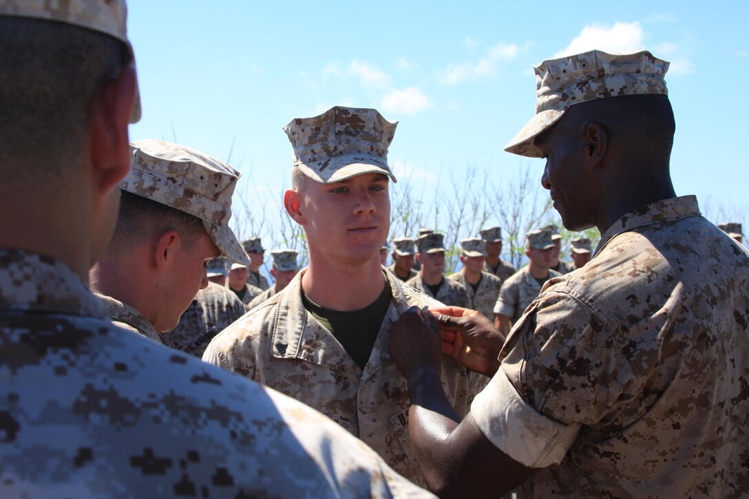 Assault Amphibian Vehicle Company Marines SSgt Matthew Walker and Cpl. Robert McCarthy pin rank insignia on newly promoted Cpl. Erick Moates Sept. 2 atop Mount Suribachi on Iwo Jima, Japan. AAV Company Marines are part of Task Force Iron Fist 4 out of Camp Fuji, Japan.