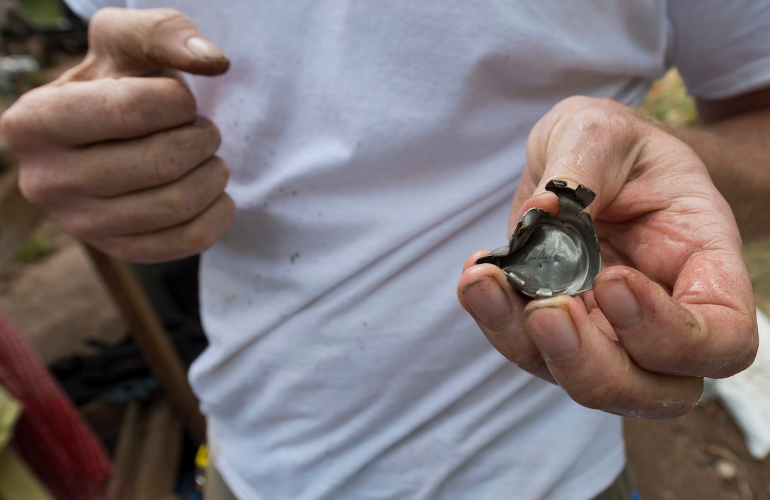 Robert Ingraham, a forensic archeologist and recovery leader with the Defense POW/MIA Accounting Agency, examines a manufacturer date stamp off of an aircraft part during a recovery mission near Riechelsdorf, Germany, Sept. 1, 2015. The team is in search of five U.S. airmen who were lost in a B-24 crash during World War II in an effort to properly identify the service members and return their remains to the United States. DoD photo by U.S. Air Force Staff Sgt. Brian Kimball
