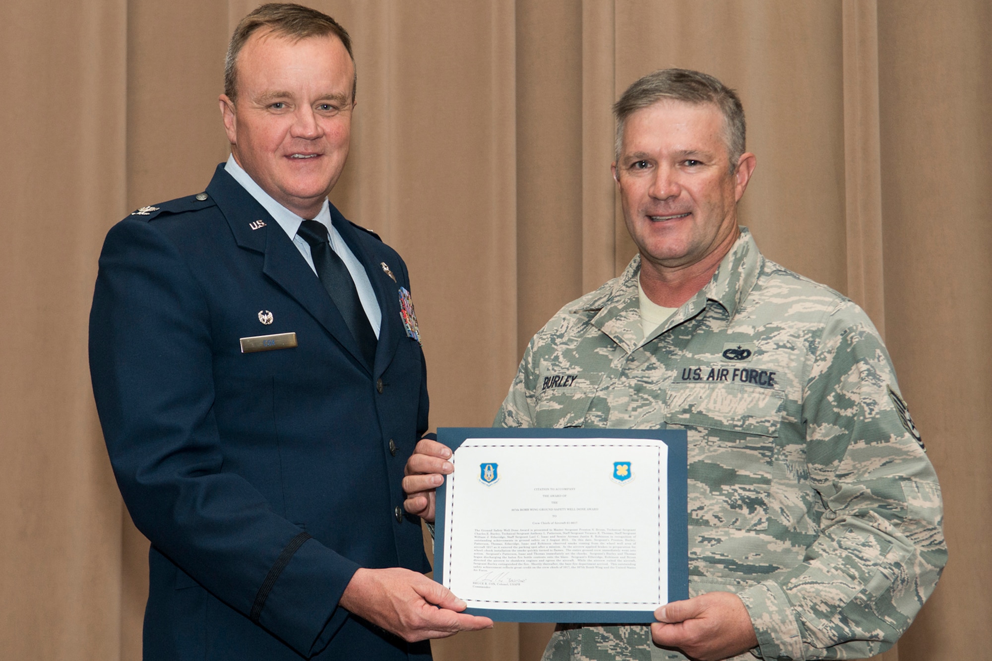 U.S. Air Force Col. Bruce Cox, 307th Bomb Wing commander, presents the Ground Safety Well Done Award to Tech. Sgt. Charles Burley during a commander's call on Sept. 13, 2015, Barksdale Air Force Base, La. Burley, a crew chief assigned to the 307th Aircraft Maintenance Squadron, received the award for his quick action during a ground safety emergency on a B-52H Stratofortress. (U.S. Air Force photo by Master Sgt. Greg Steele/Released)