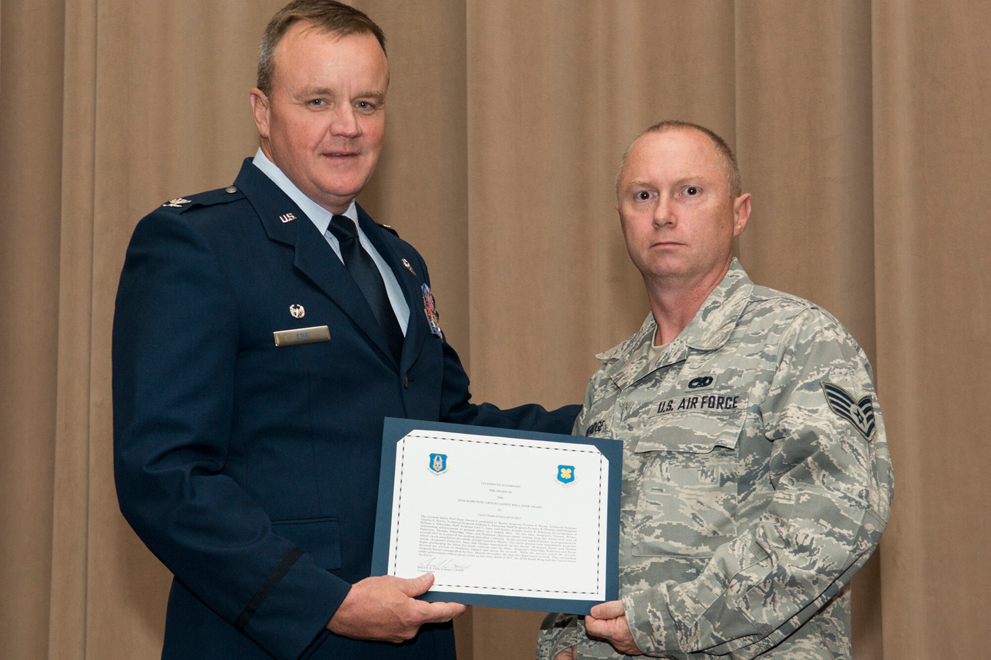 U.S. Air Force Col. Bruce Cox, 307th Bomb Wing commander, presents the Ground Safety Well Done Award to Staff Sgt. William Etheridge during a commander's call on Sept. 13, 2015, Barksdale Air Force Base, La. Etheridge, a crew chief assigned to the 307th Aircraft Maintenance Squadron, received the award for his quick action during a ground safety emergency on a B-52H Stratofortress. (U.S. Air Force photo by Master Sgt. Greg Steele/Released)