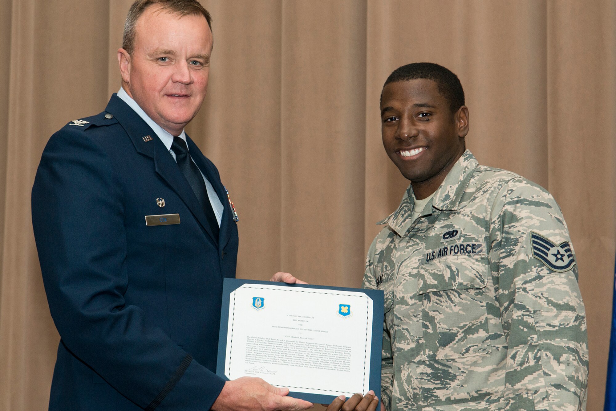 U.S. Air Force Col. Bruce Cox, 307th Bomb Wing commander, presents the Ground Safety Well Done Award to Staff Sgt. Lael Isaac during a commander's call on Sept. 13, 2015, Barksdale Air Force Base, La. Isaac, a crew chief assigned to the 307th Aircraft Maintenance Squadron, received the award for his quick action during a ground safety emergency on a B-52H Stratofortress. (U.S. Air Force photo by Master Sgt. Greg Steele/Released)
