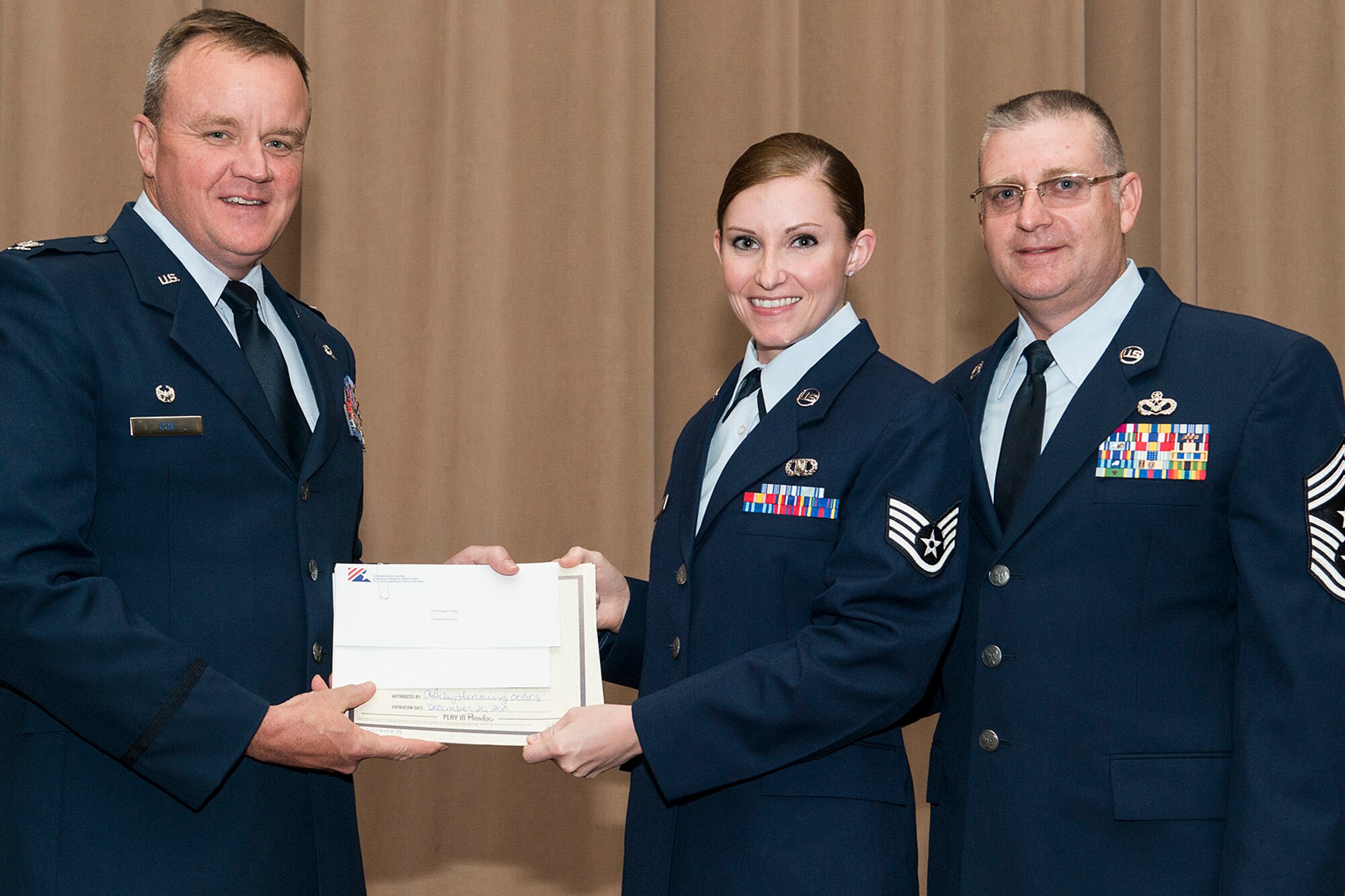 U.S. Air Force Col. Bruce Cox, 307th Bomb Wing commander, presents Senior Airman Meagan Kay with a collection of awards during a Commander's Call on Sept. 13, 2015, Barksdale Air Force Base, La. Kay is assigned to the 307th Operations Support Squadron and was selected as the Airman of the Quarter for the period covering April to June 2015. (U.S. Air Force photo by Master Sgt. Greg Steele/Released)