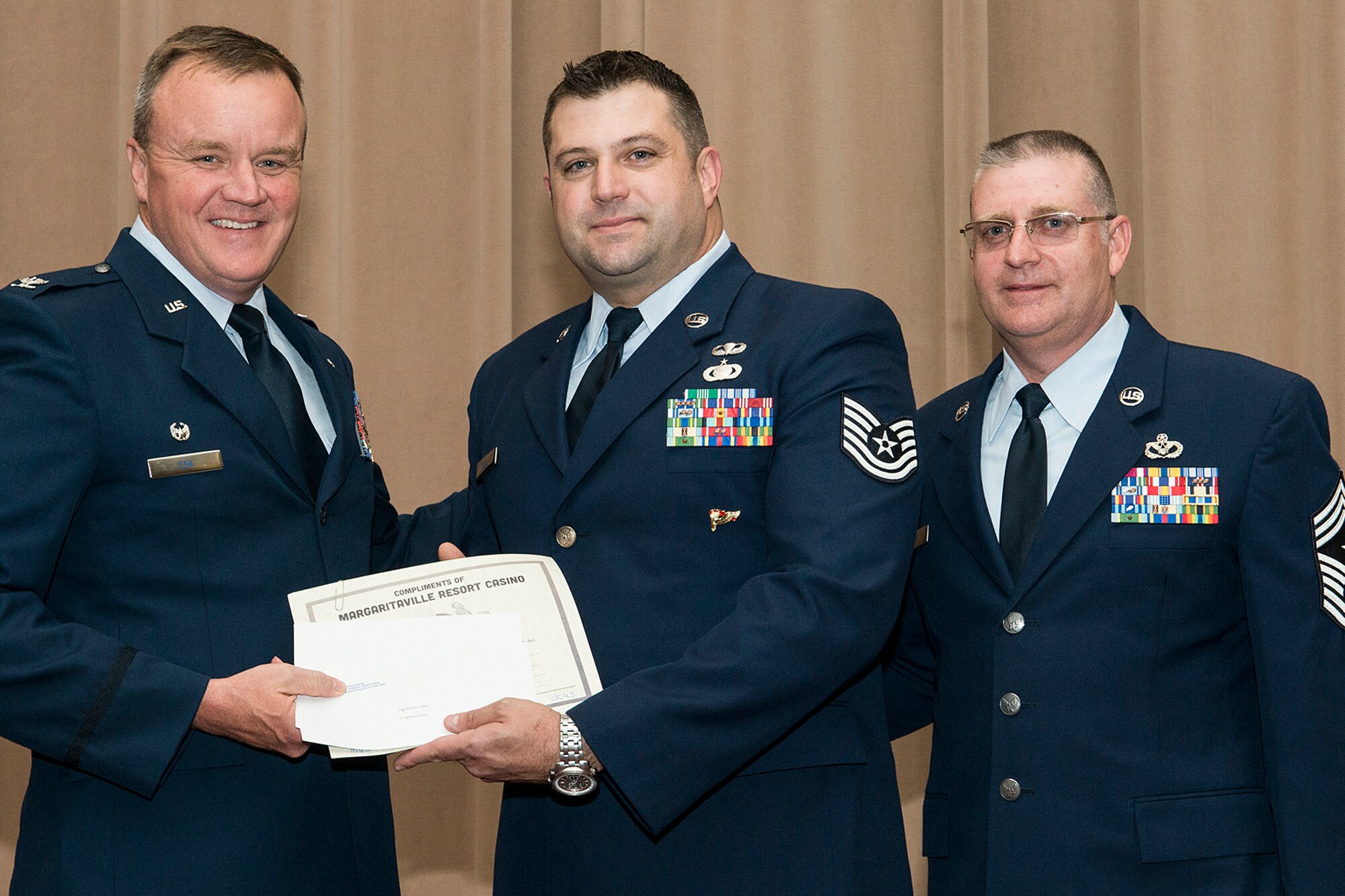 U.S. Air Force Col. Bruce Cox, 307th Bomb Wing commander, presents Tech. Sgt. Marvin Bell with a collection of awards during a Commander's Call on Sept. 13, 2015, Barksdale Air Force Base, La. Bell is assigned to the 307th Operations Support Squadron and was selected as the Noncommissioned Officer of the Quarter for the period covering April to June 2015. (U.S. Air Force photo by Master Sgt. Greg Steele/Released)