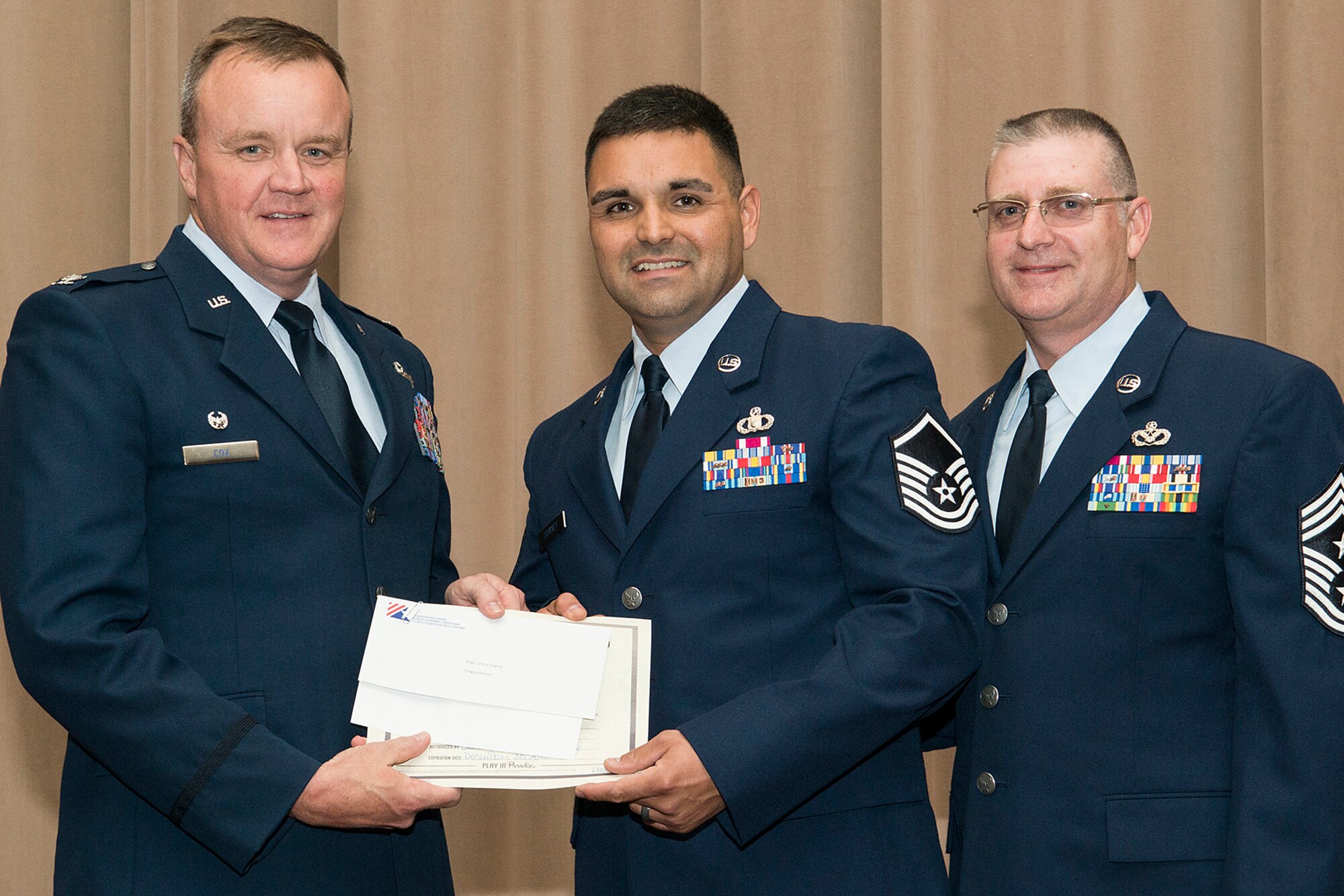 U.S. Air Force Col. Bruce Cox, 307th Bomb Wing commander, presents Master Sgt. Curtis Downey with a collection of awards during a Commander's Call on Sept. 13, 2015, Barksdale Air Force Base, La. Downey is assigned to the 307th Operations Support Squadron and was selected as the  Senior Noncommissioned Officer of the Quarter for the period covering April to June 2015. (U.S. Air Force photo by Master Sgt. Greg Steele/Released)