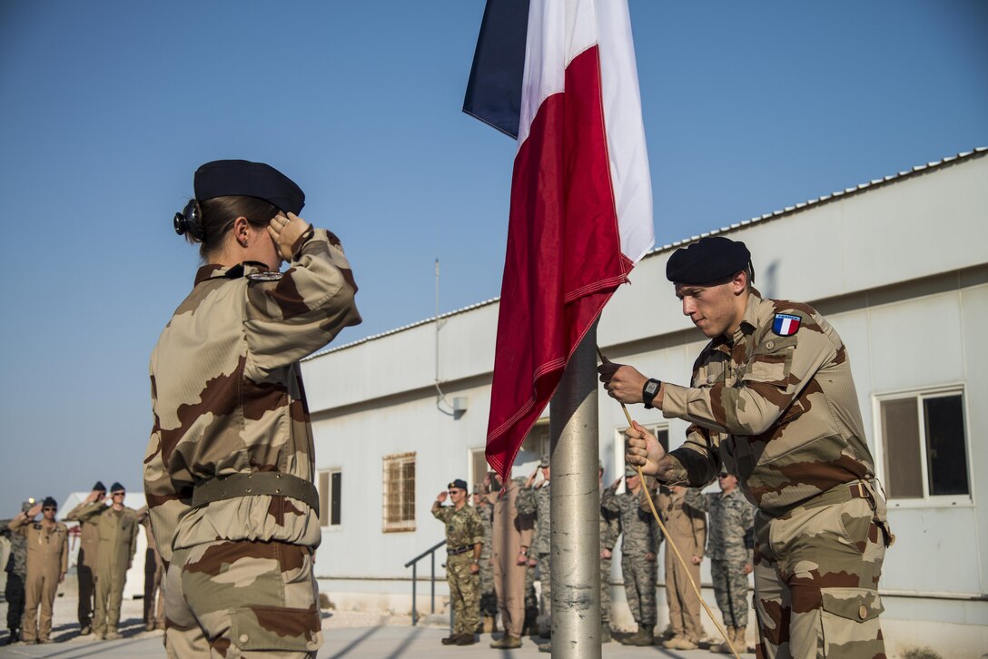 French Air Force members raise their flag to mark the start of the duty day during the French National Day Parade September 14, 2015 at Al Udeid Air Base, Qatar. The parade was the commemoration of the death of WWI French pilot Capt Georges Guynemer, in Polkapelle, on September 11th, 1917. Since 1923, the French Air Force has organized a parade to start or close the day in remembrance of him. (U.S. Air Force photo by Tech. Sgt. Rasheen Douglas)