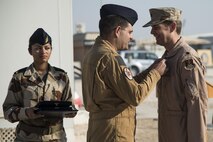 Col. Pascal Sotty, 609th Combined Air and Operations Center French Air Force Detachment senior officer, presents the French National Defense medal to Lt. Col. David Haworth, Combined Air Operations Center chief of current of operations division, at the French National Day Parade September 14, 2015 at Al Udeid Air Base, Qatar. The parade was the commemoration of the death of WWI French pilot Capt. Georges Guynemer, in Polkapelle, on September 11th, 1917. Since 1923, the French Air Force has organized a parade to start or close the day in remembrance of him.  (U.S. Air Force photo by Tech. Sgt. Rasheen Douglas)