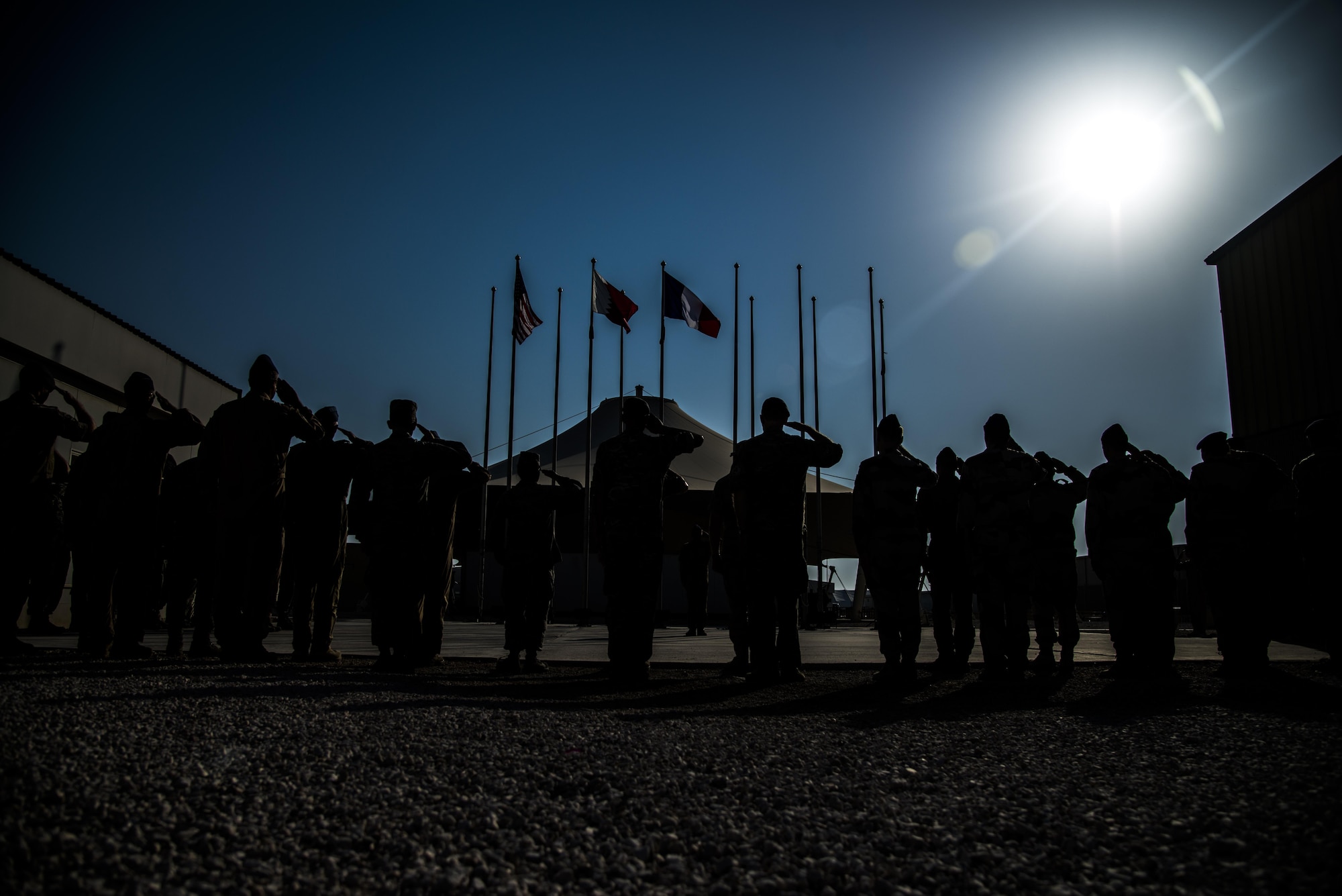 Combined Air Operations Center members stand in formation saluting the French Flag during the French National Day Parade September 14, 2015 at Al Udeid Air Base, Qatar. The parade was the commemoration of the death of WWI French pilot Capt Georges Guynemer, in Polkapelle, on September 11th, 1917. Since 1923, the French Air Force has organized a parade to start or close the day in remembrance of him.  (U.S. Air Force photo by Tech. Sgt. Rasheen Douglas)