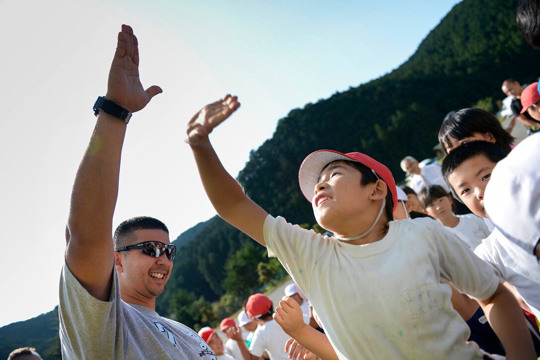 A volunteer raises his hand high above local students after a "thank you" presentation at Kanuma City, Tochigi Prefecture, Sept. 15, 2015. Students at the local elementary school made a speech and sang a song to thank the volunteers for their efforts in the community. U.S. Air Force photo by Staff Sgt. Cody H. Ramirez 